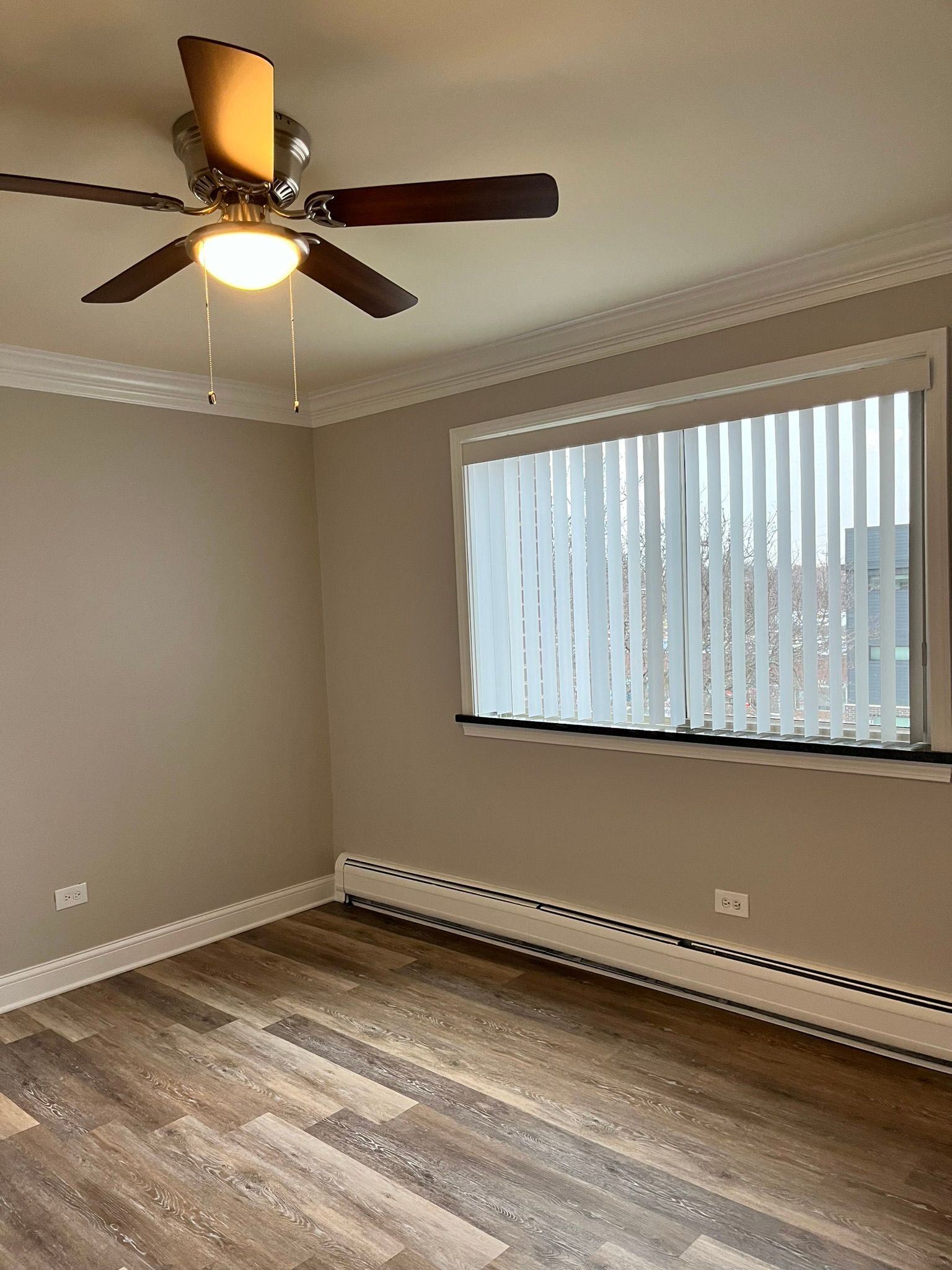 An empty room with a ceiling fan and a window.