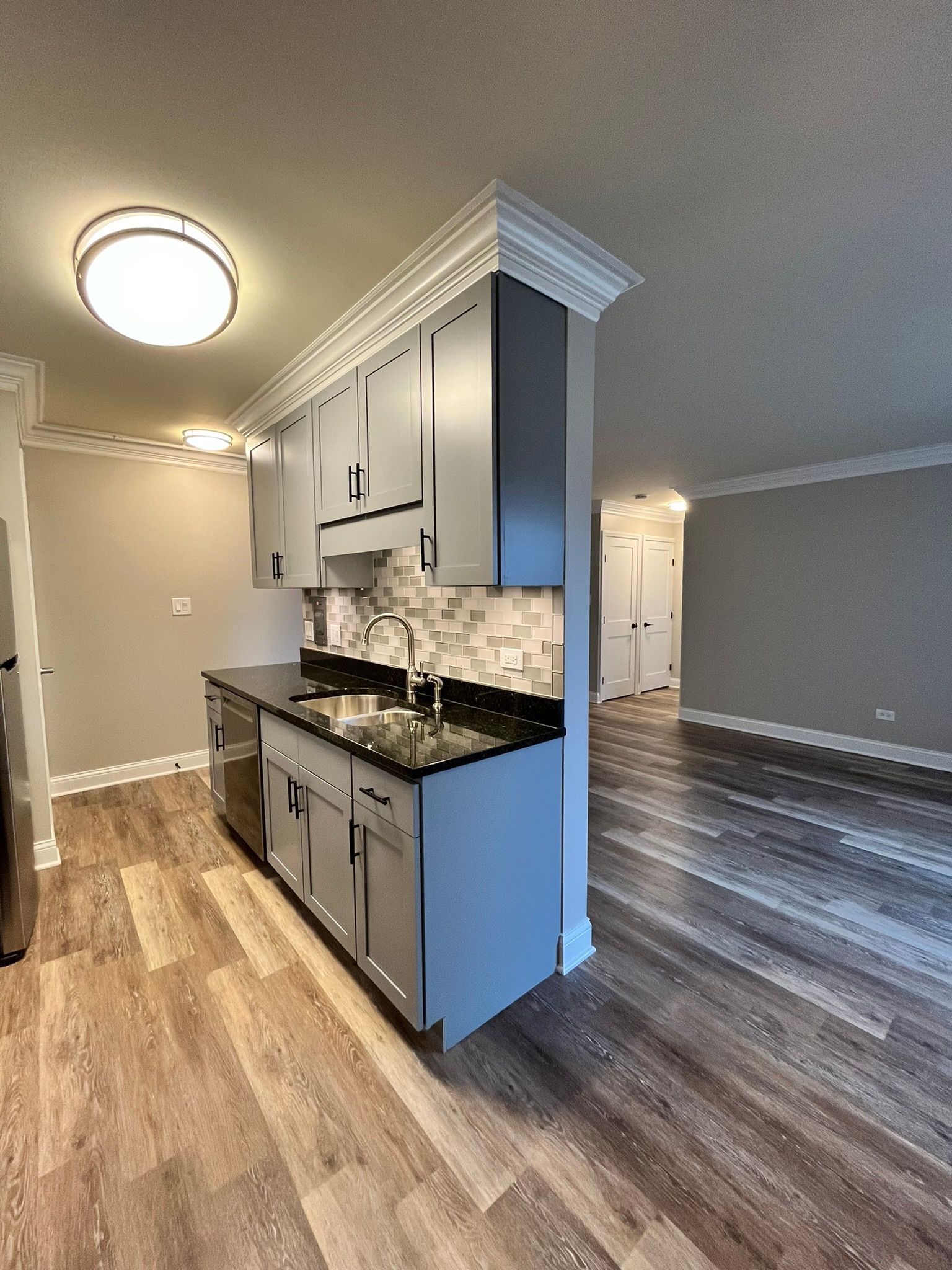 A kitchen with a sink , dishwasher , and cabinets.