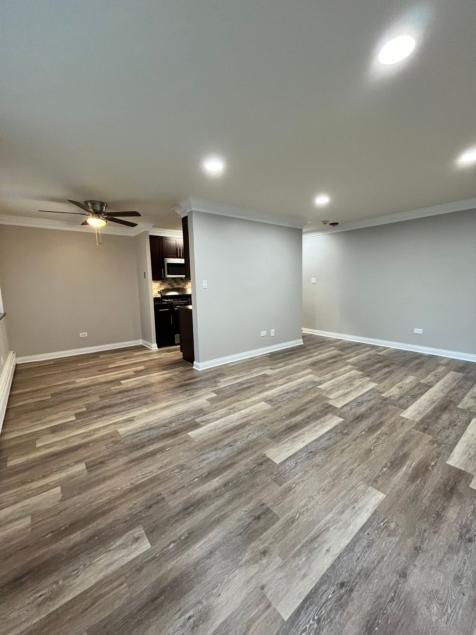 A living room with hardwood floors and a ceiling fan.