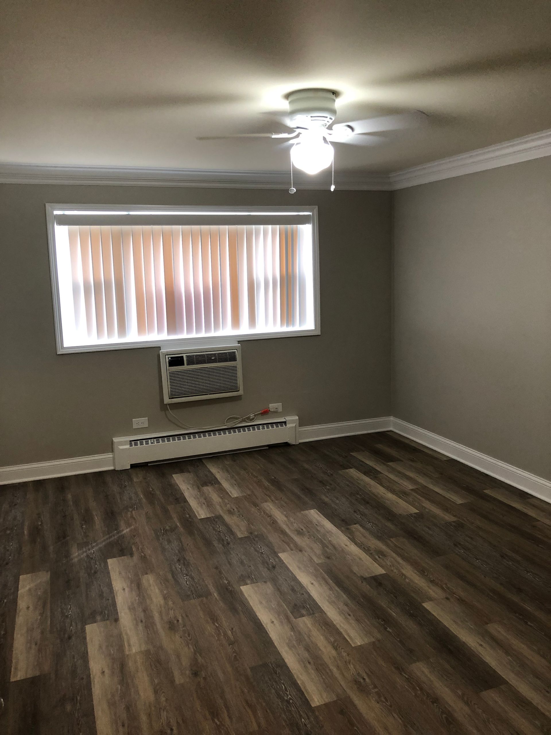a living room with hardwood floors , a window and a ceiling fan .