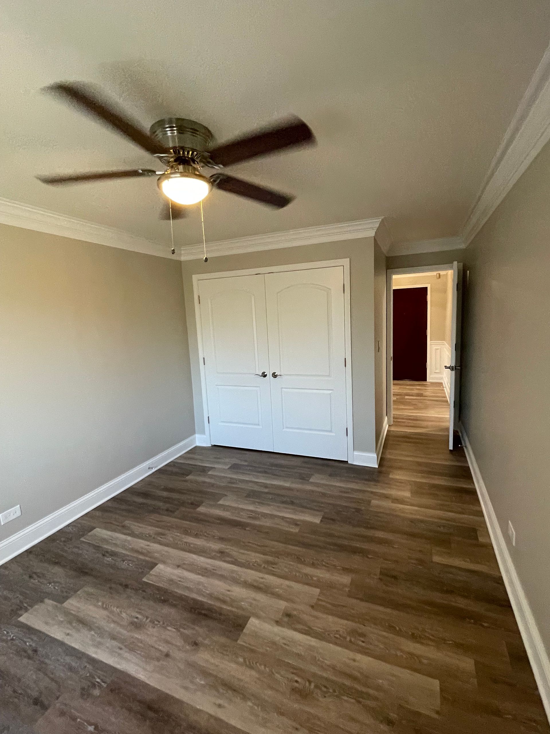 a bedroom with hardwood floors and a ceiling fan .