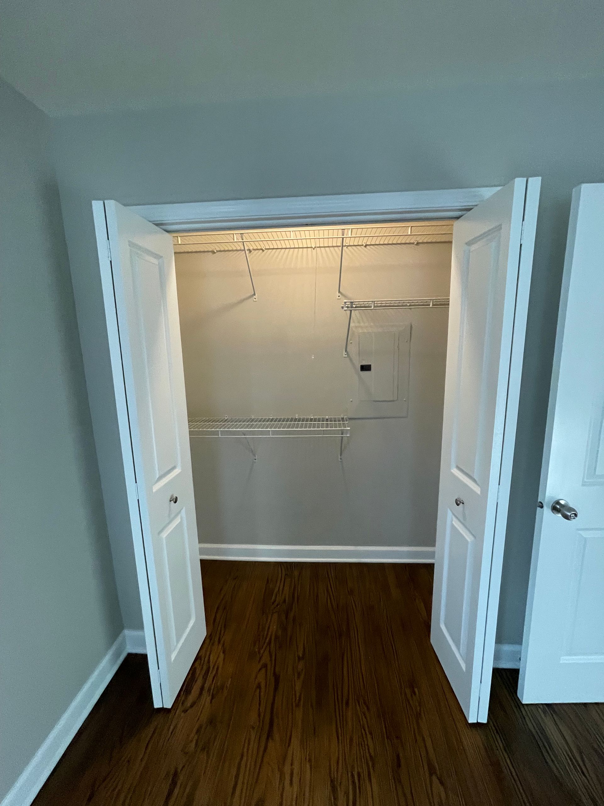 a closet with the doors open and a wooden floor .