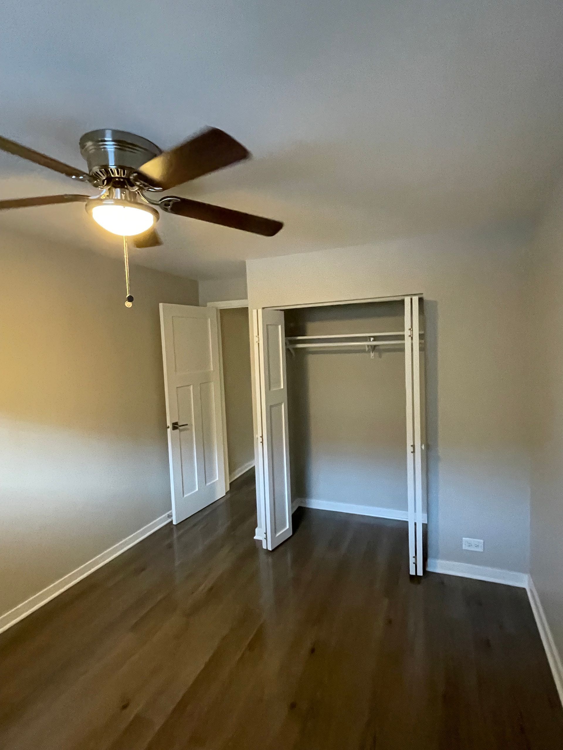an empty bedroom with a ceiling fan and a closet .