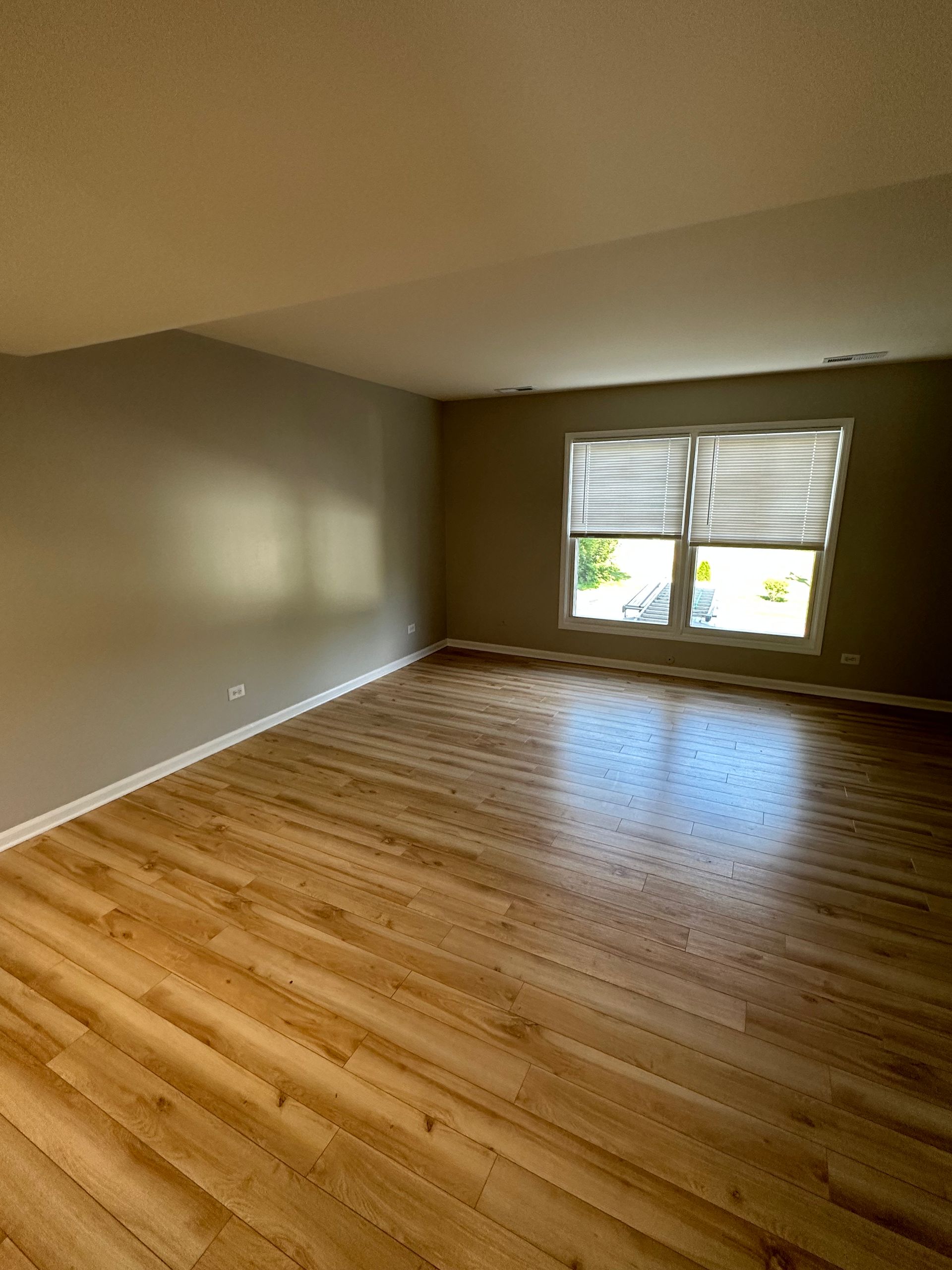 an empty living room with hardwood floors and a window .