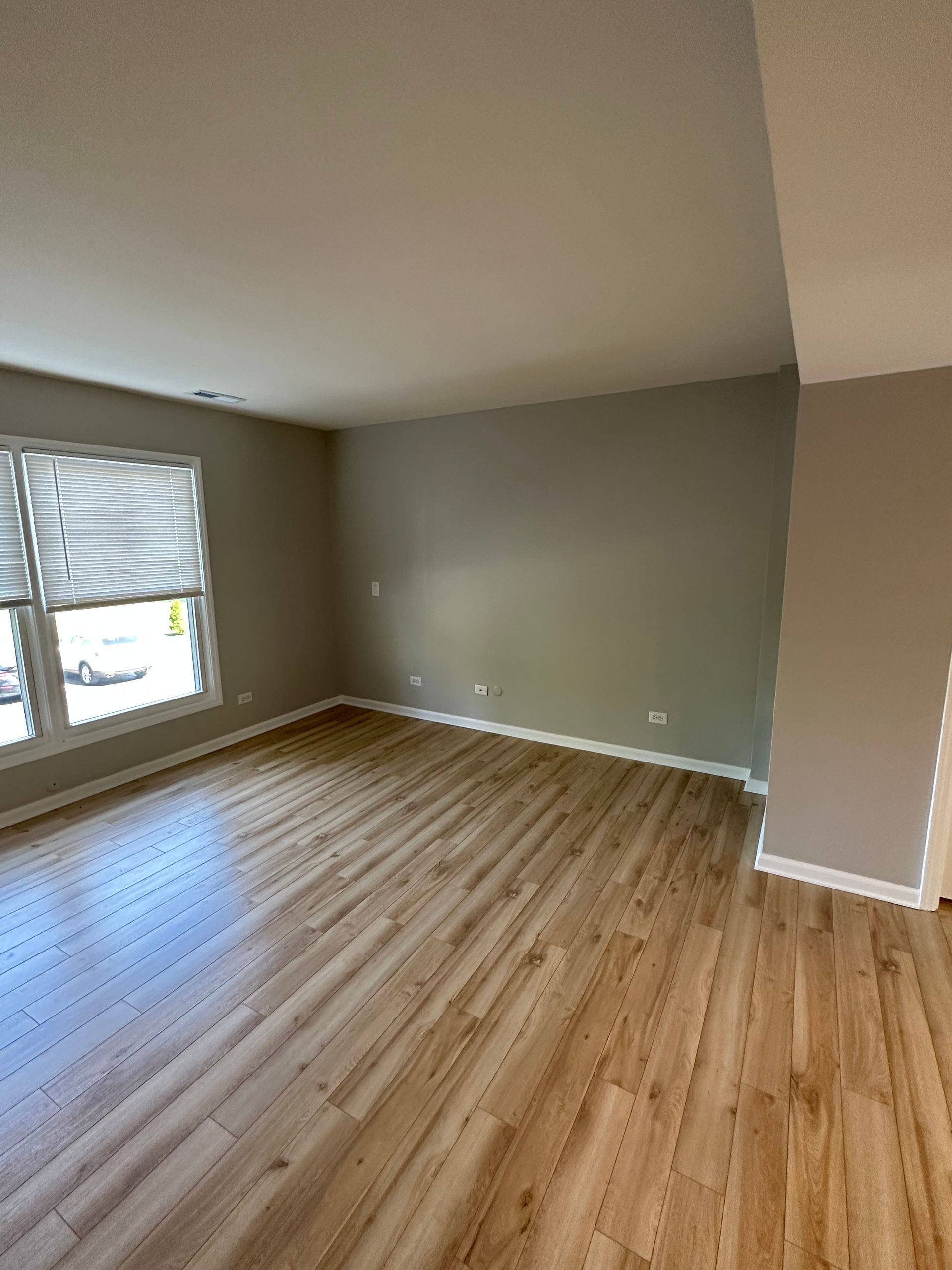 an empty living room with hardwood floors and gray walls .