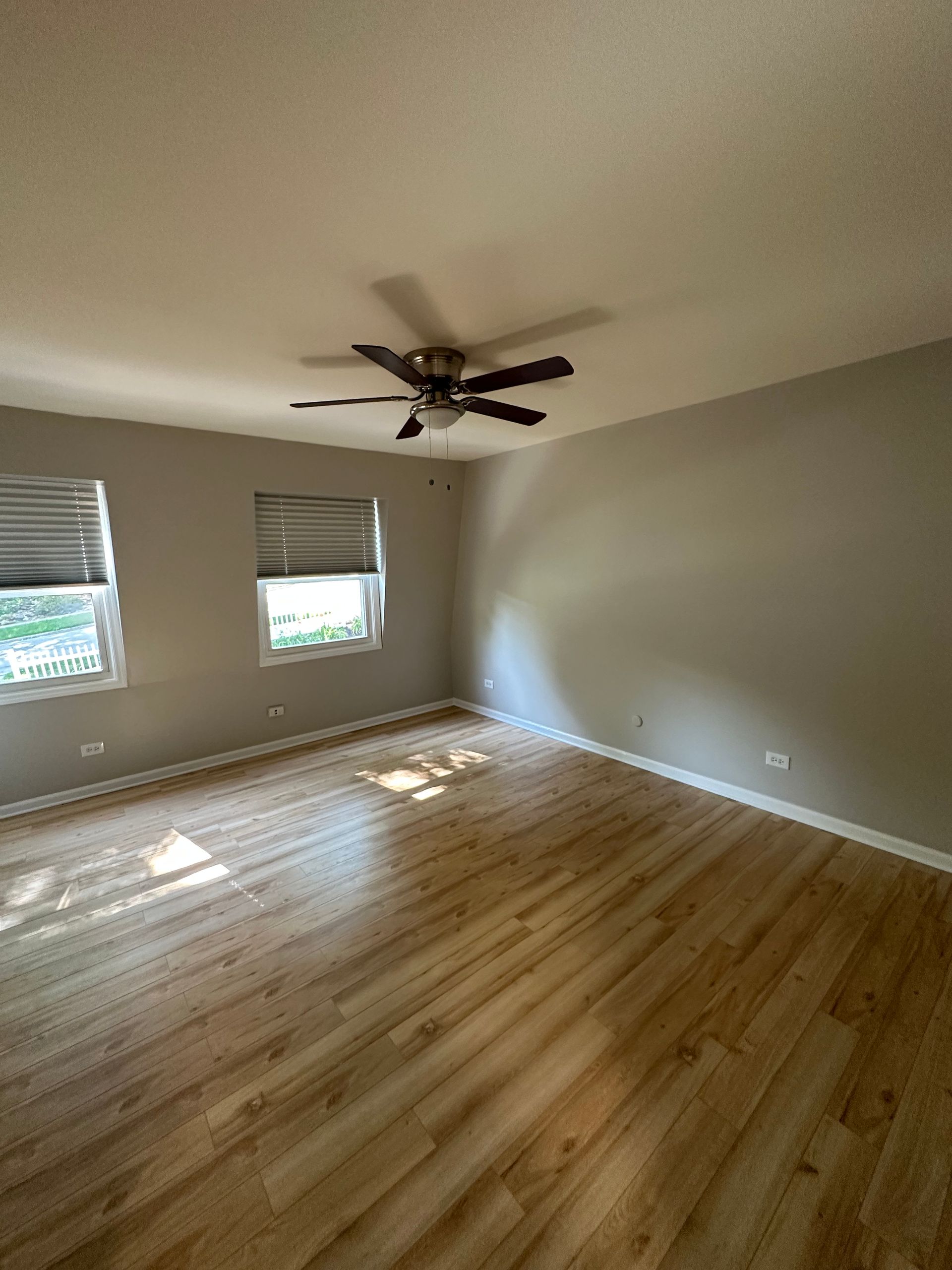an empty room with hardwood floors and a ceiling fan .