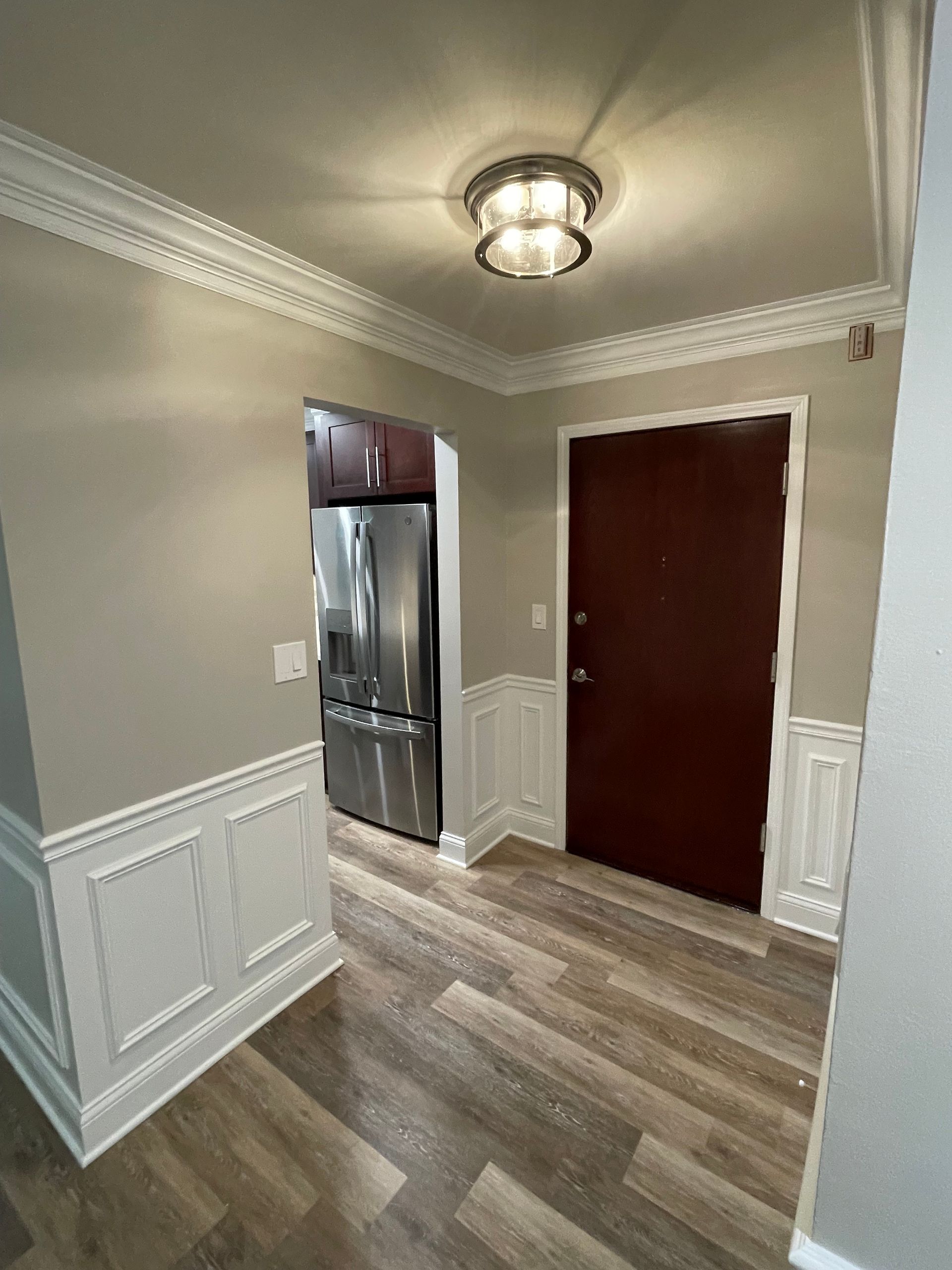 a hallway in a house with a refrigerator and a door .