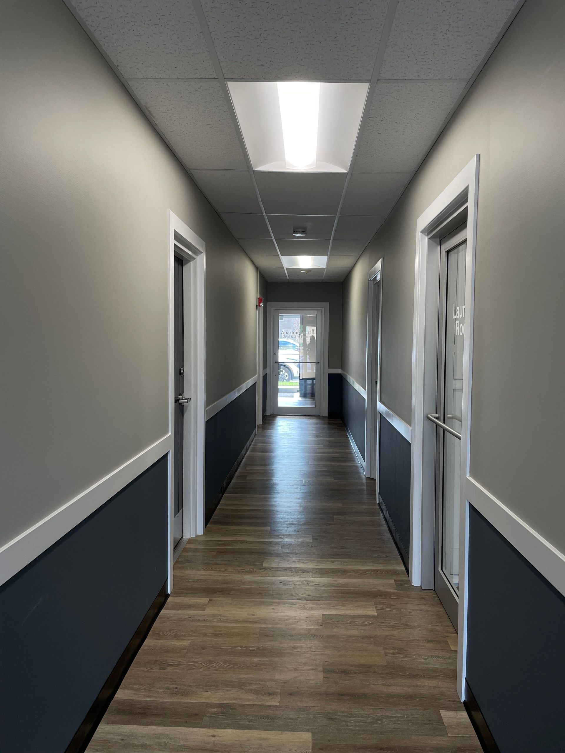 a long hallway with wooden floors and gray walls