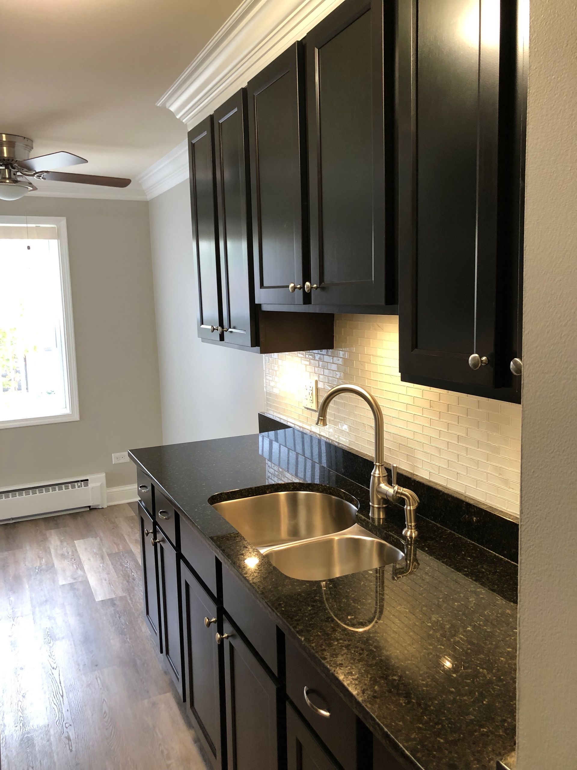 a kitchen with black cabinets and a stainless steel sink .