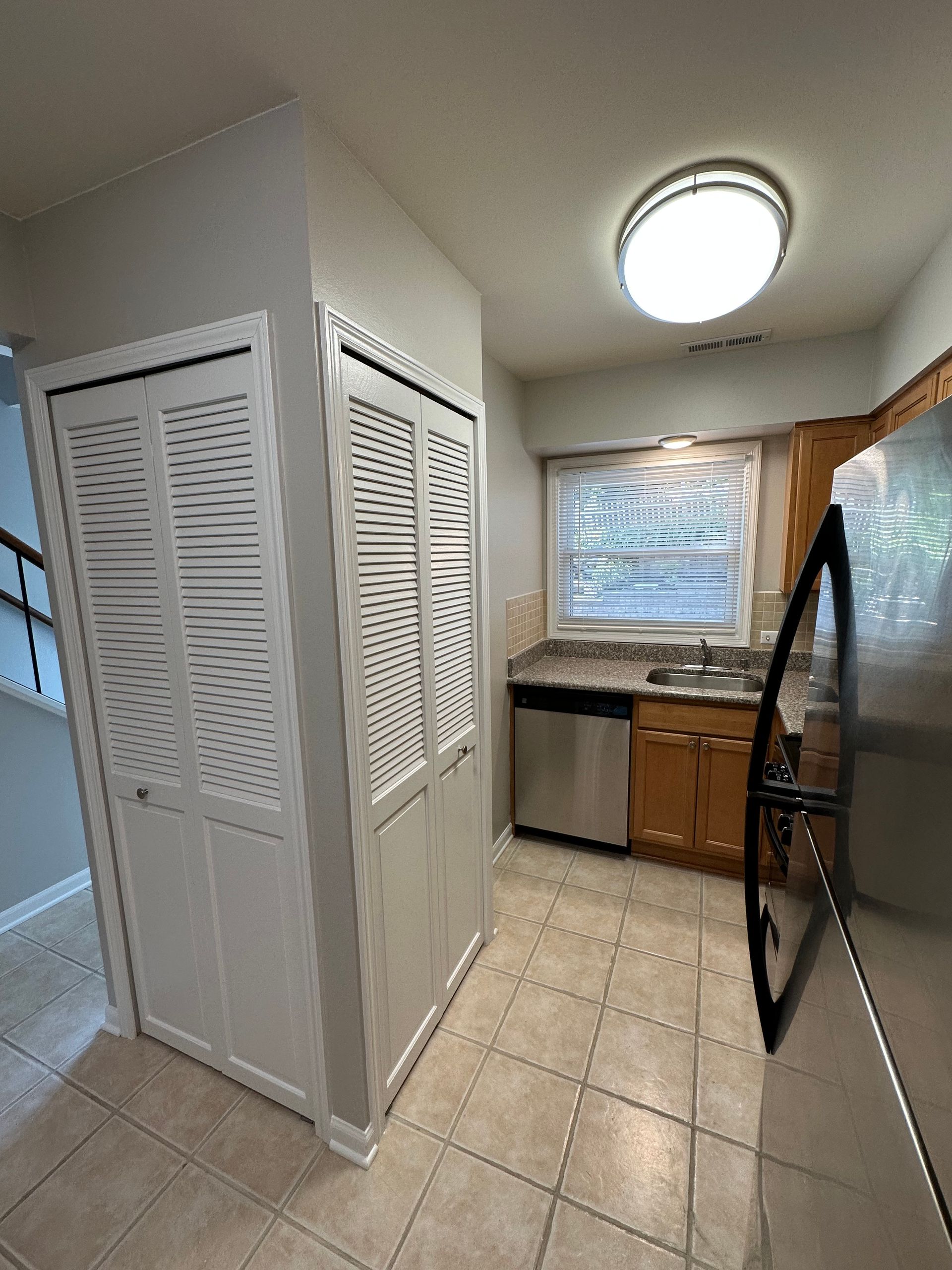 a kitchen with a refrigerator , dishwasher , sink , cabinets and a window .