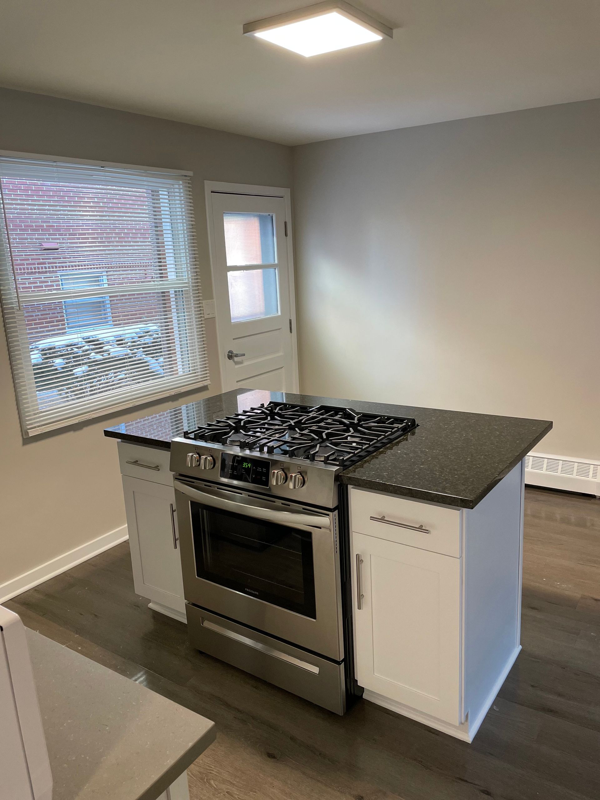 a kitchen with a stove and a window with blinds