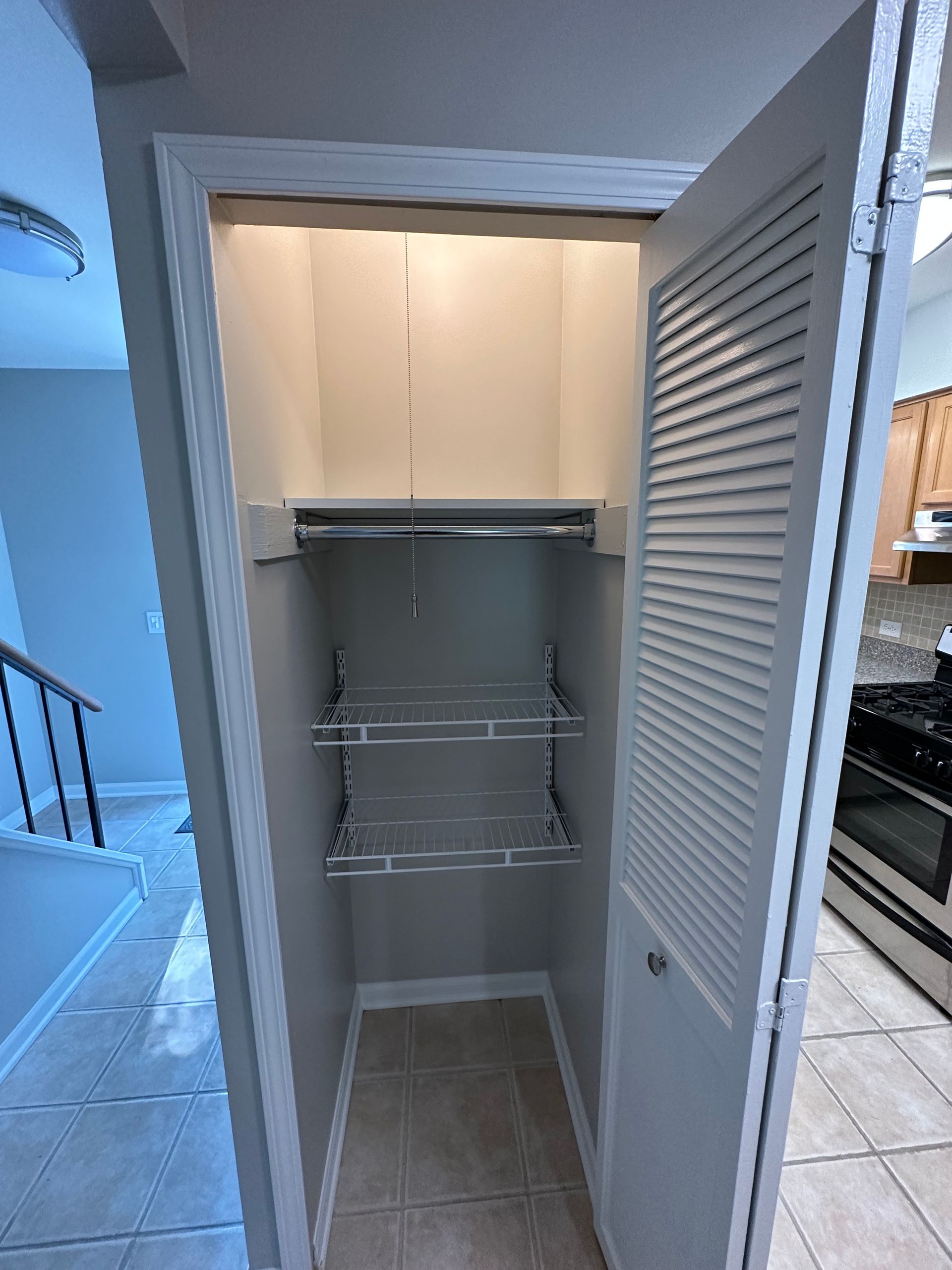 a closet in a house with a stove and stairs in the background .