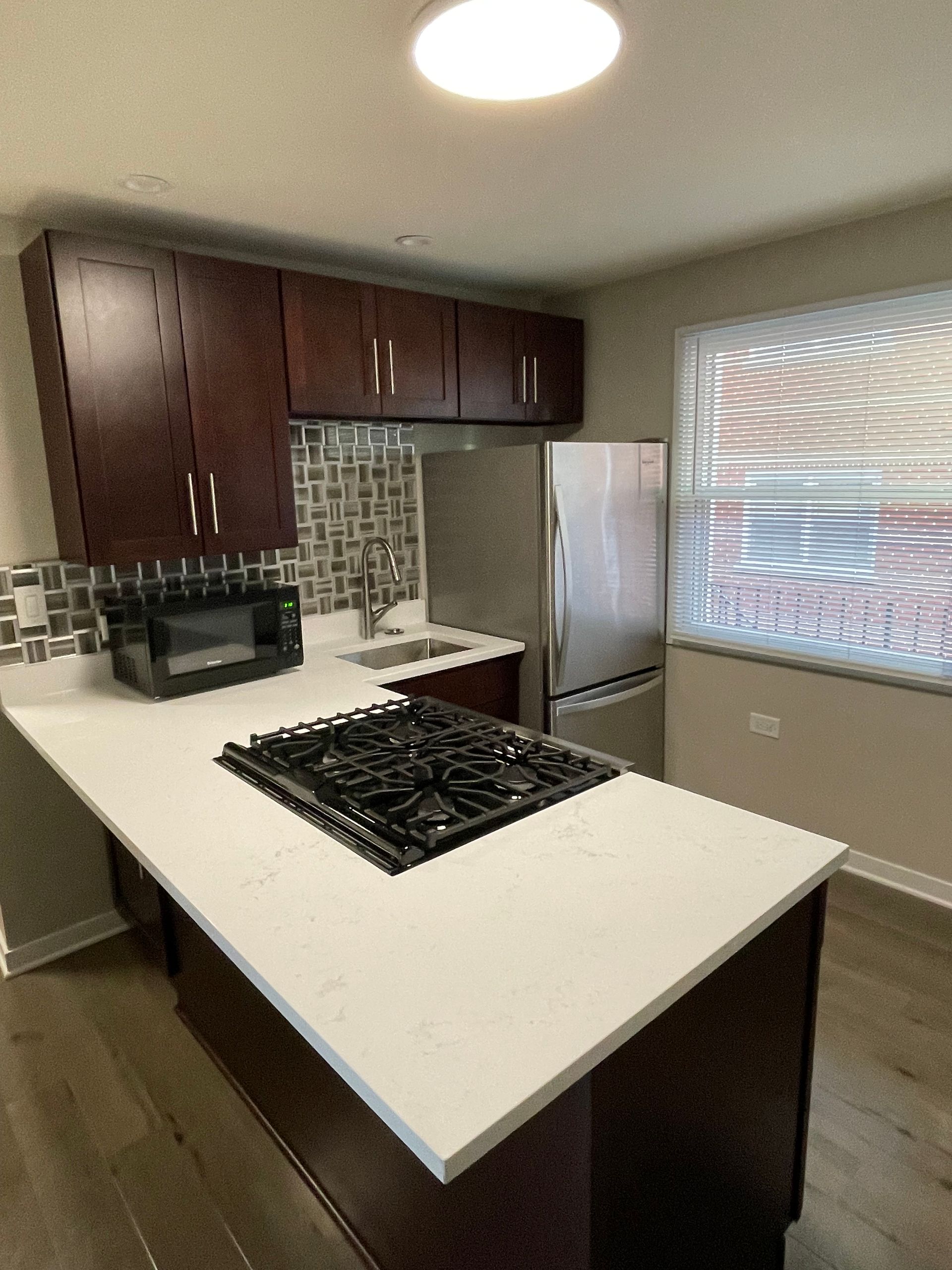 a kitchen with a stove top oven , refrigerator , microwave and sink .
