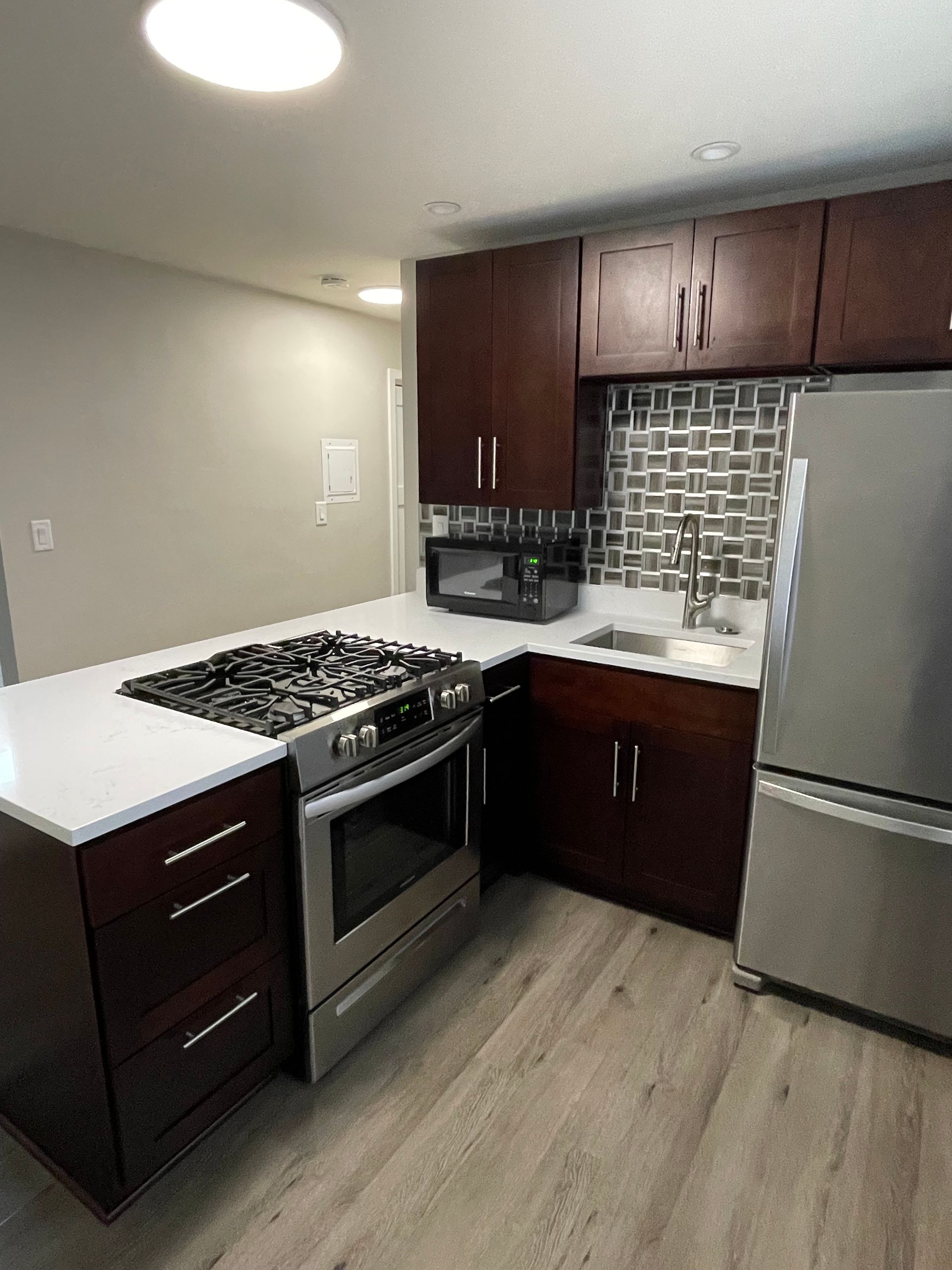 a kitchen with a stove , refrigerator , sink and microwave .