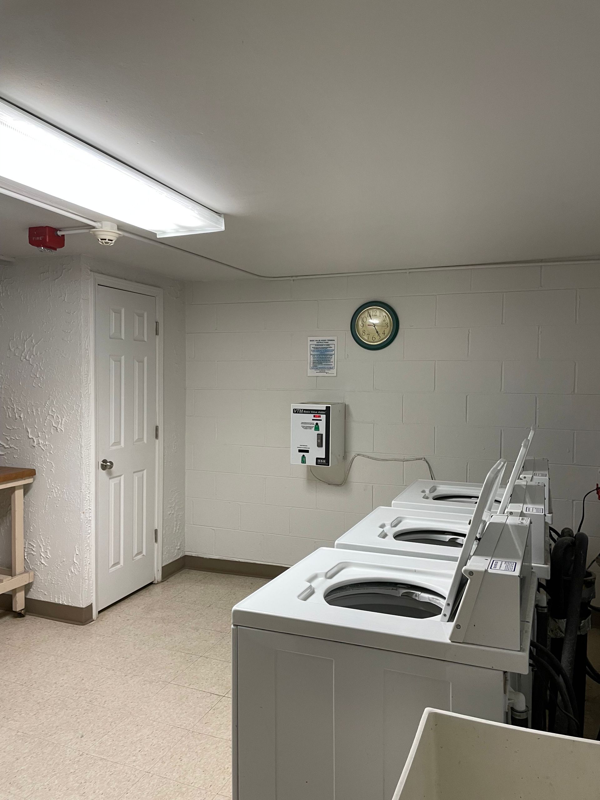 a laundromat with a row of washing machines and a clock on the wall .