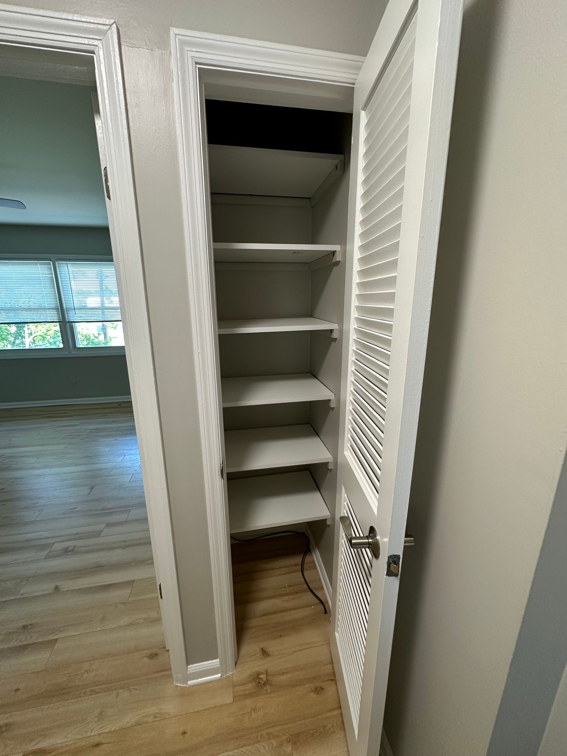 a closet with a door open and shelves inside of it .