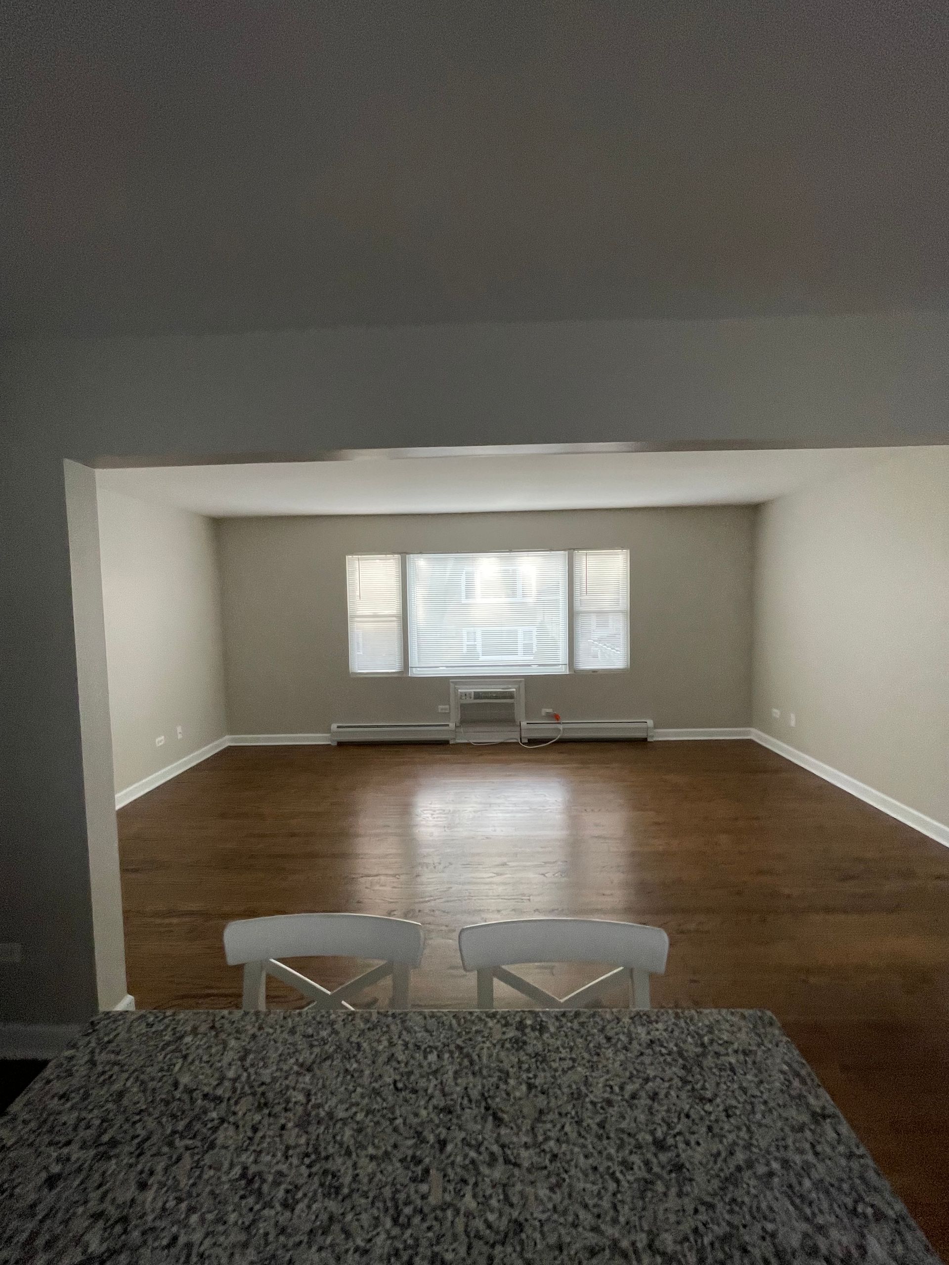 an empty living room with hardwood floors and a large window .
