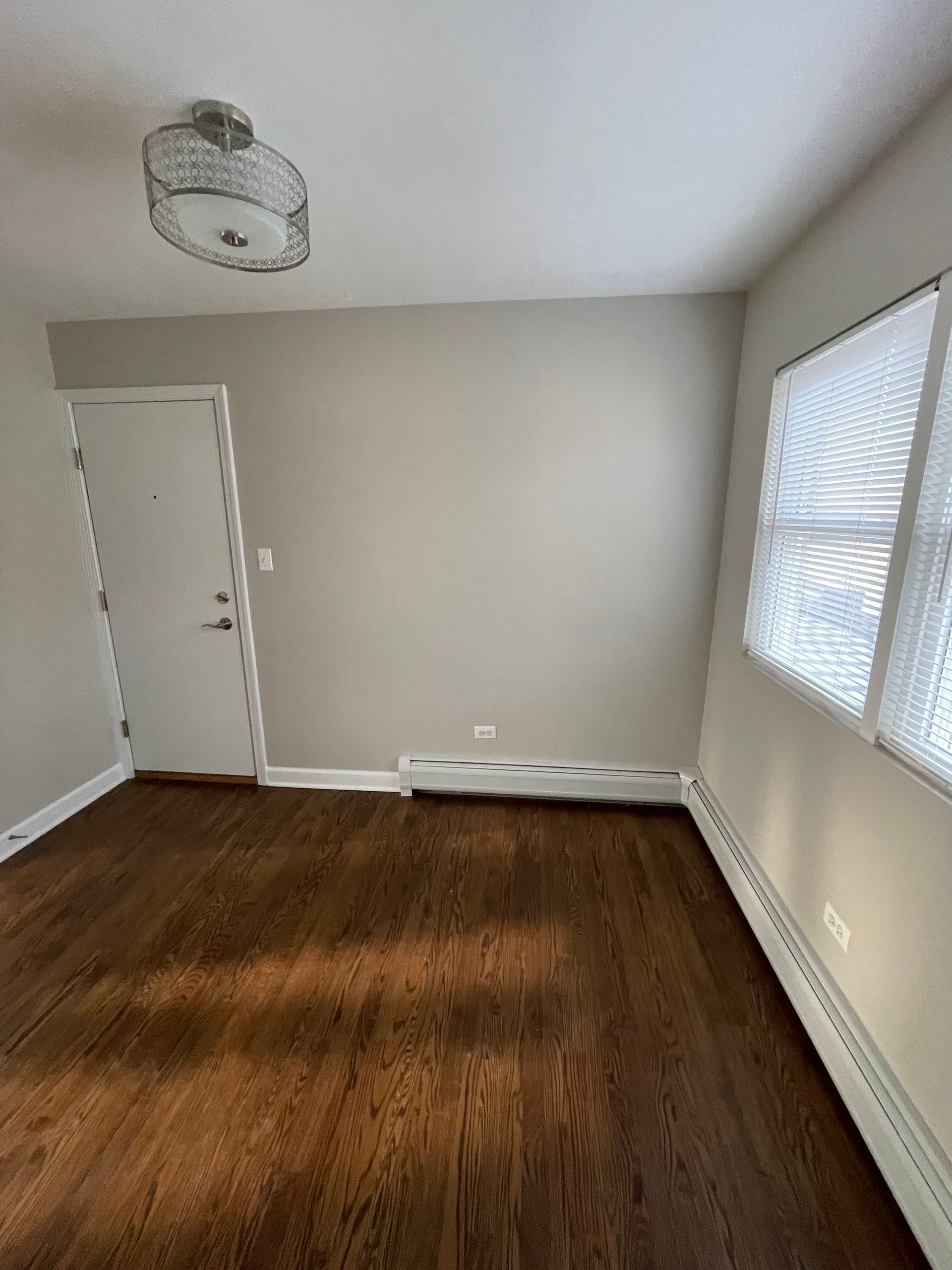 an empty room with hardwood floors and a door .