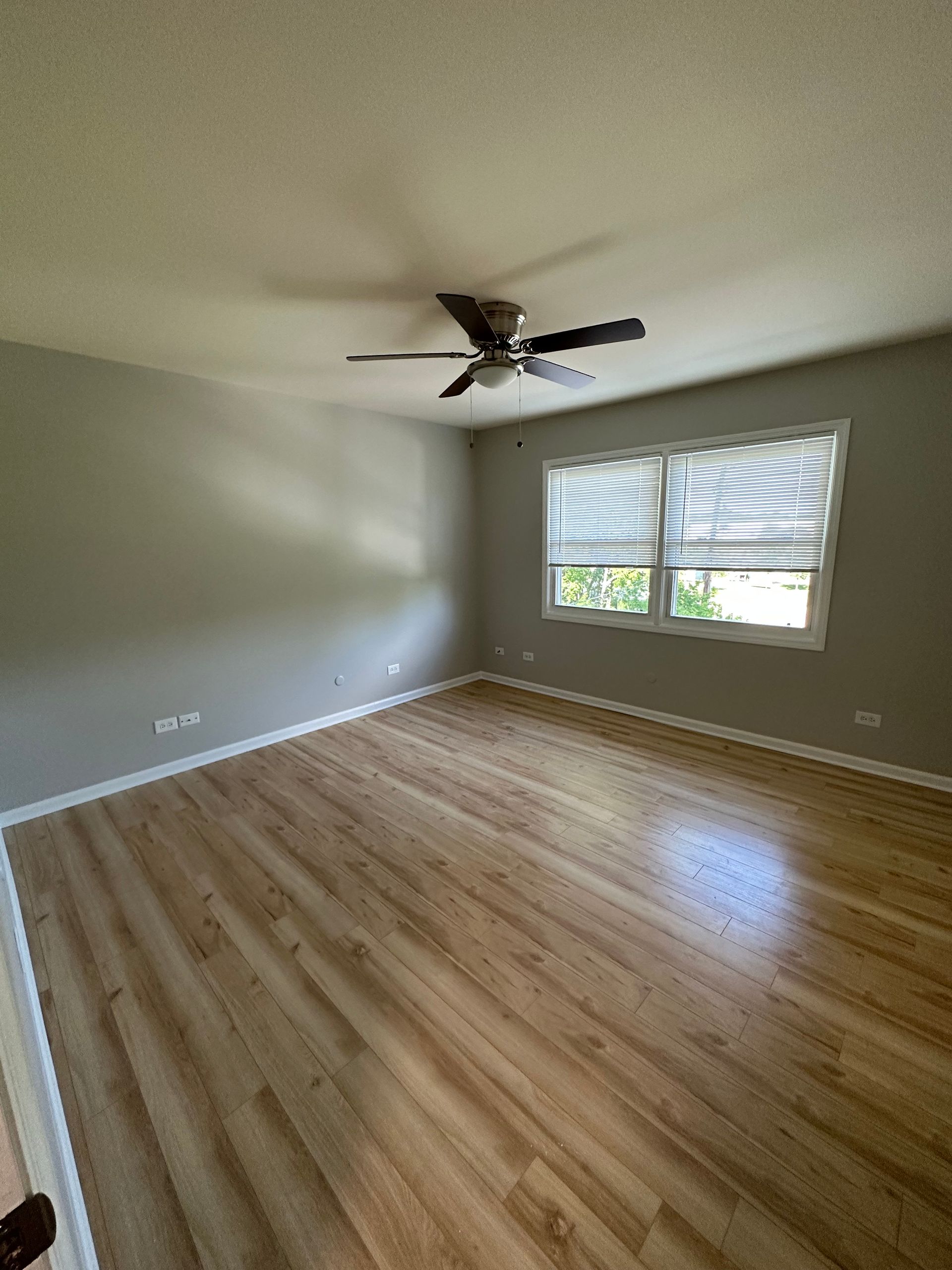 an empty living room with hardwood floors and a ceiling fan .