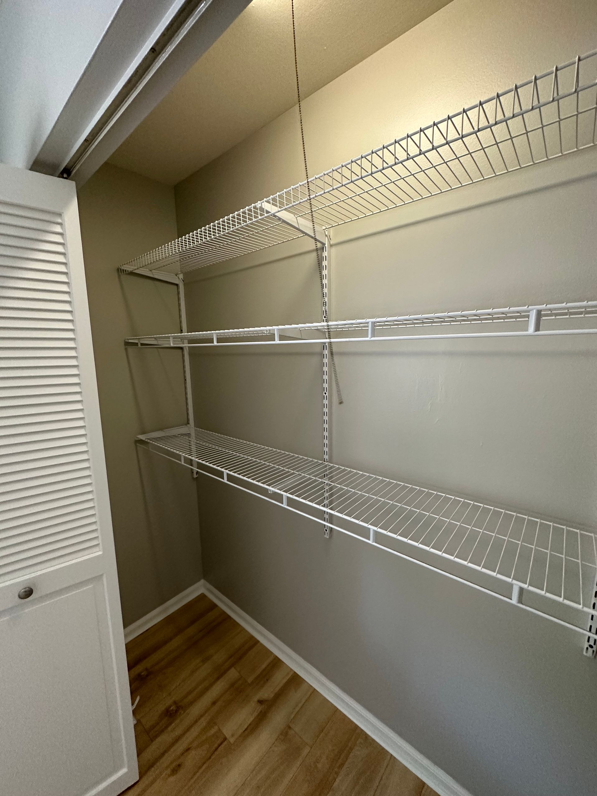 a walk in closet with lots of shelves and a door .