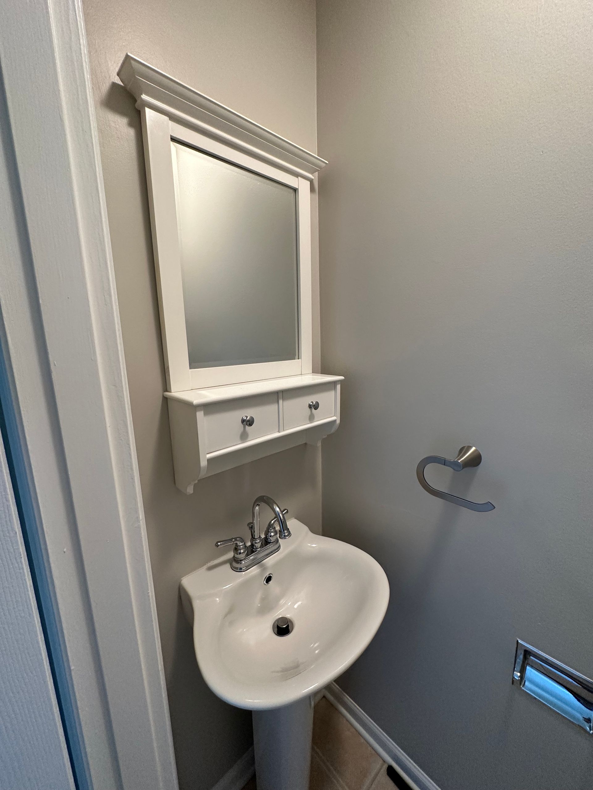 a bathroom with a sink , mirror and towel rack .