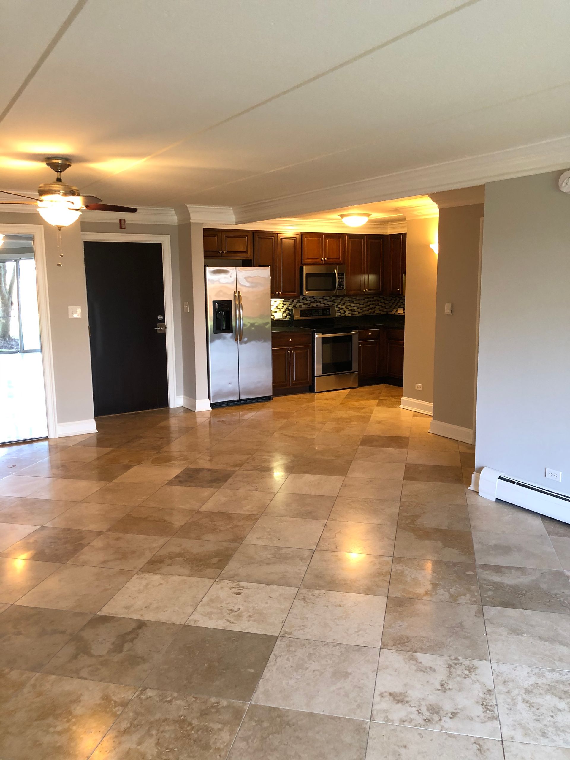 An empty living room with a kitchen in the background.