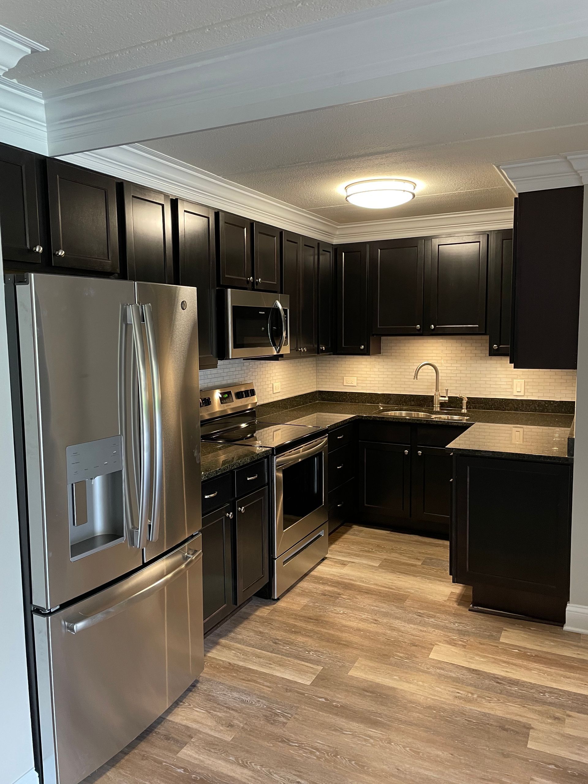 A kitchen with black cabinets and stainless steel appliances