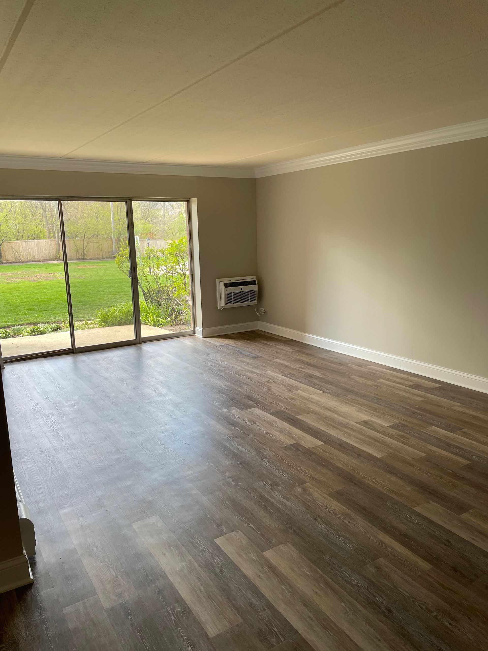 An empty living room with hardwood floors and sliding glass doors.