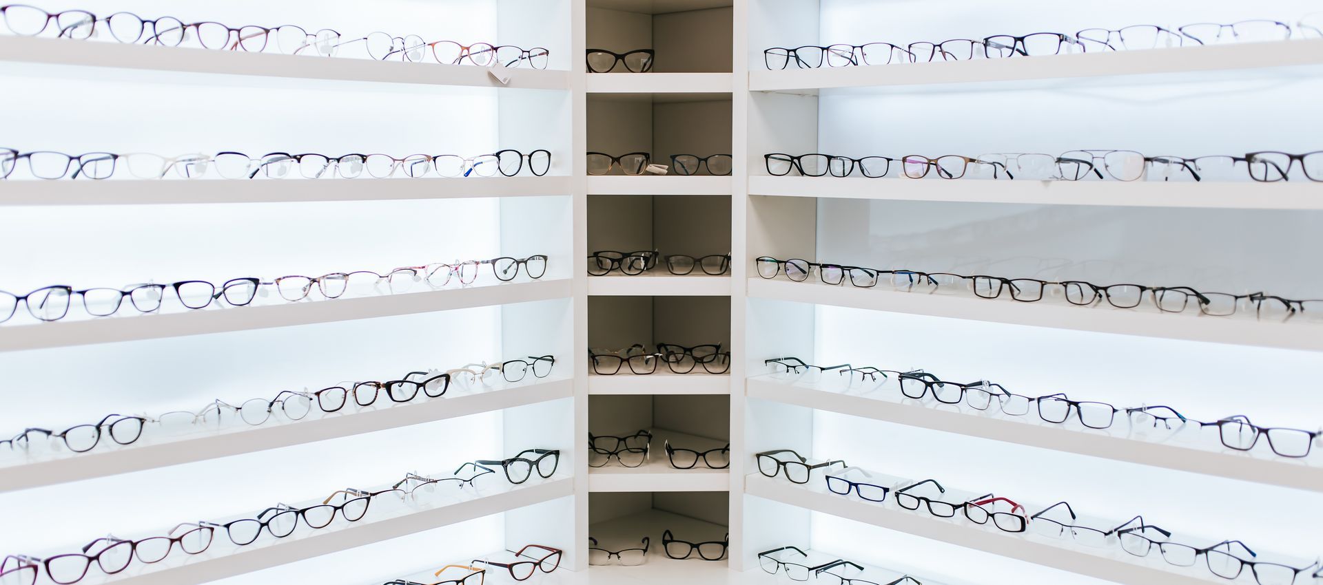 Eyeglass frames displayed on illuminated shelves in an optical store