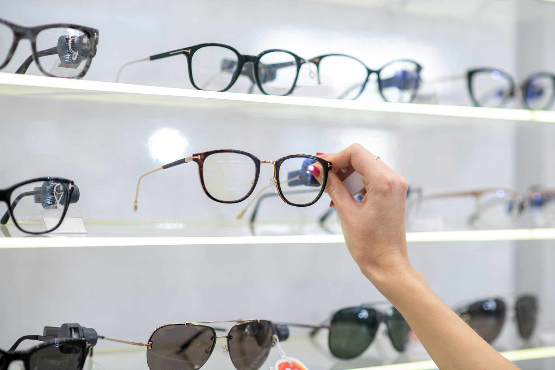 Hand selecting eyeglass frames from a display shelf in an optical store. Hand selecting eyeglass frames from a display shelf in an optical store.