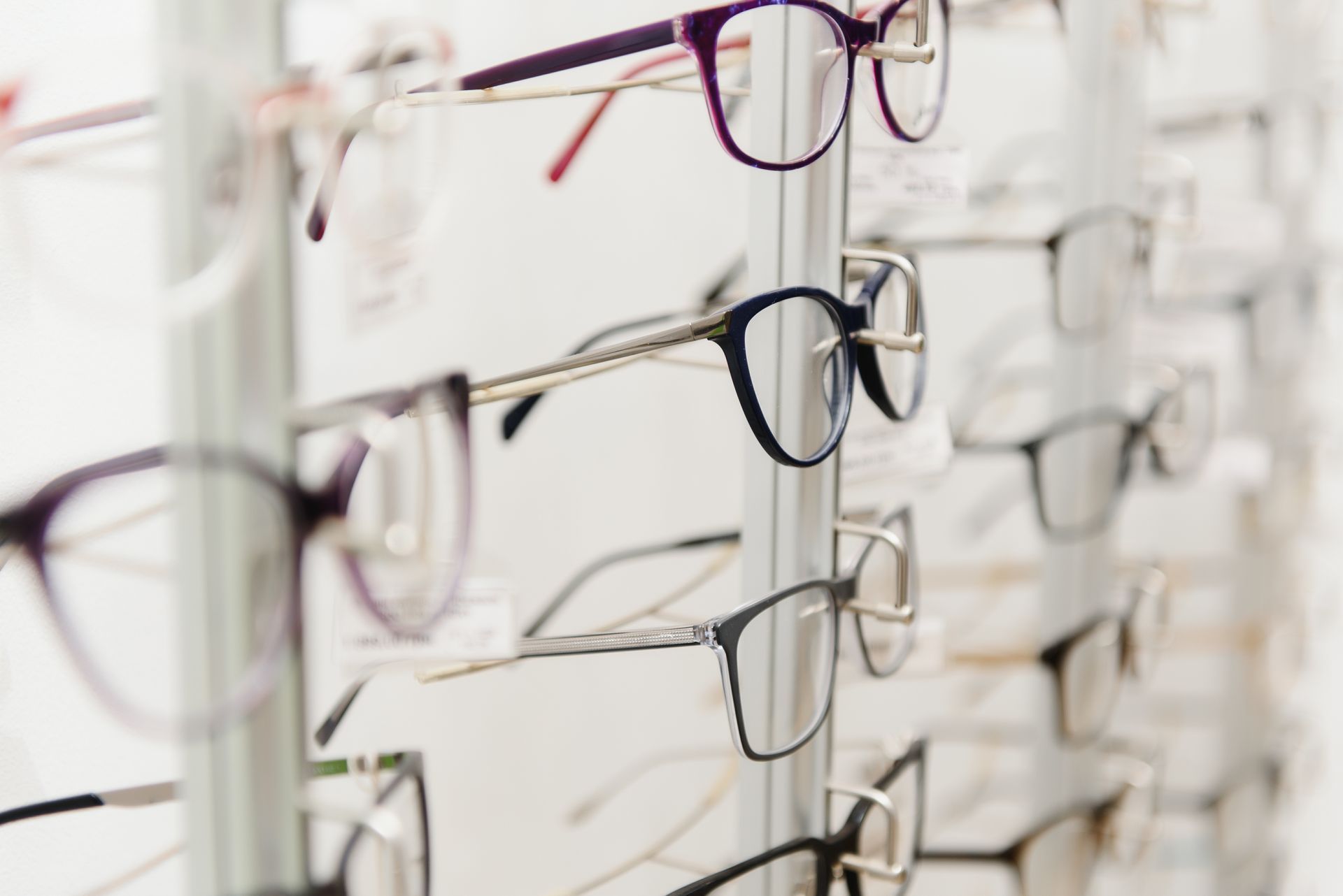 Eyeglasses displayed on a retail wall rack showcasing various stylish frame designs.