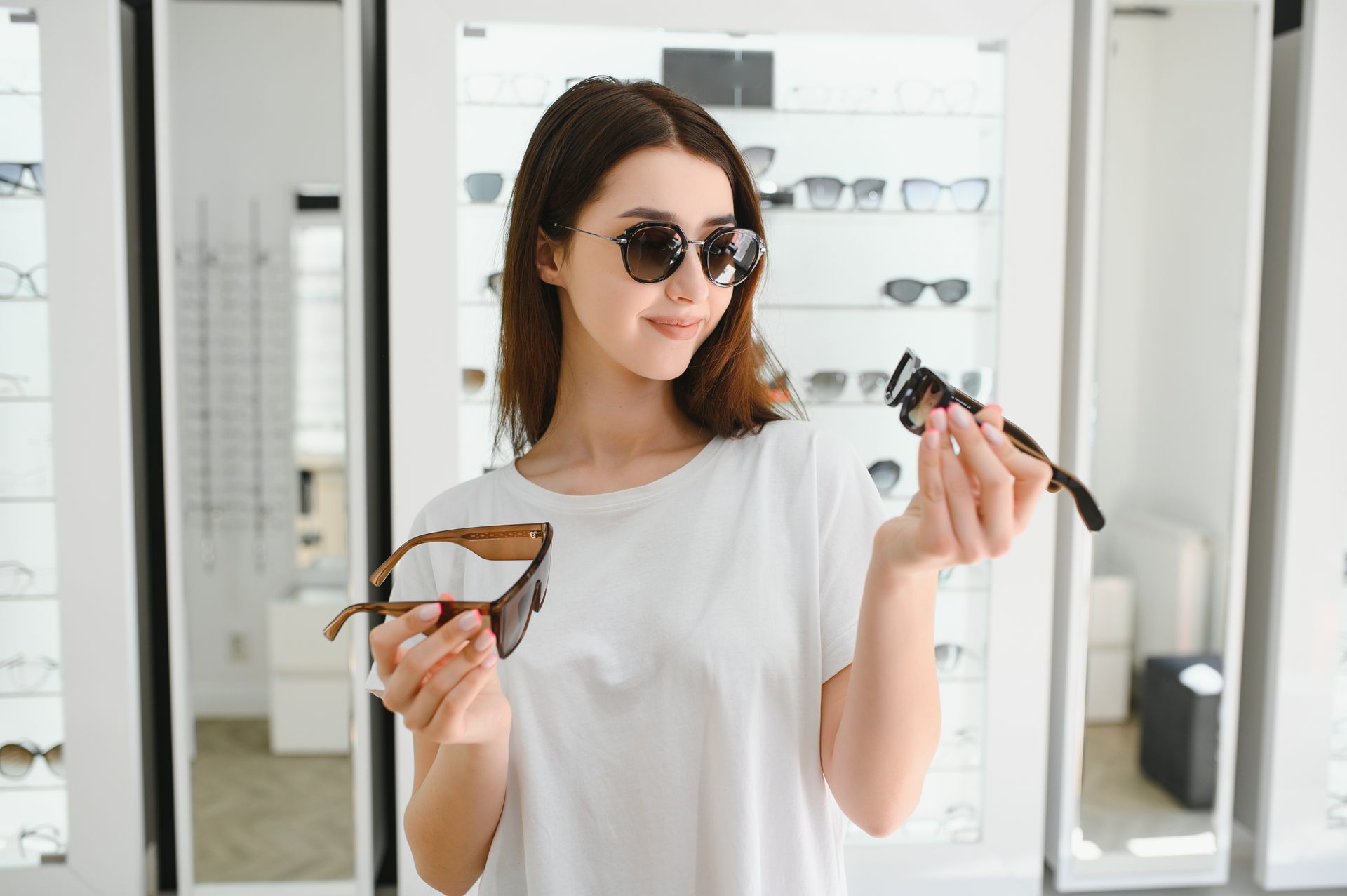 Person comparing sunglasses while browsing eyewear in an optical store