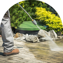Man Using High-Pressure Washer to Clean a Concrete Driveway