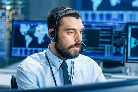 A man wearing a headset is sitting in front of a computer.