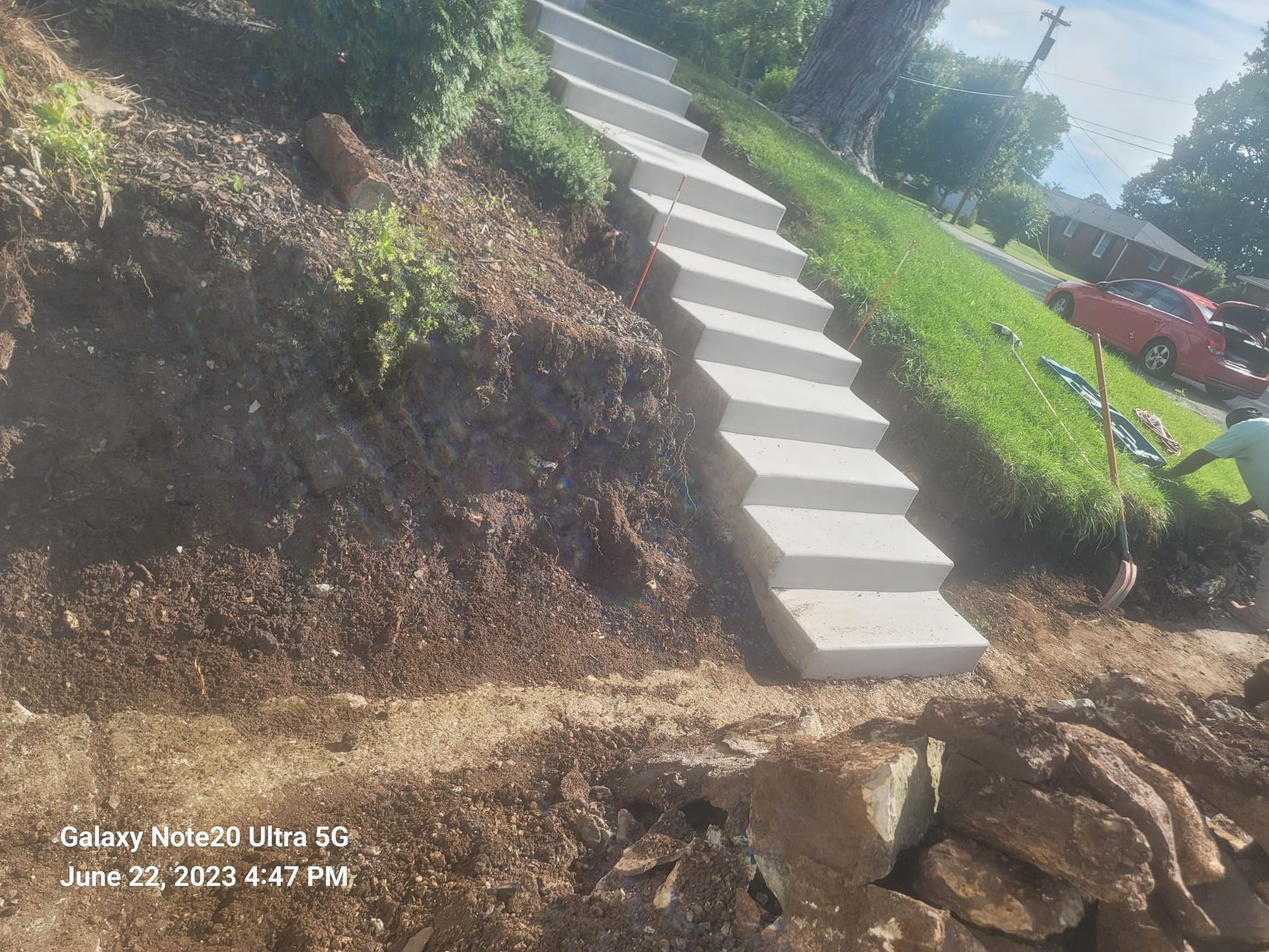 Concrete stairs built into a hillside, rising through dirt and grass.
