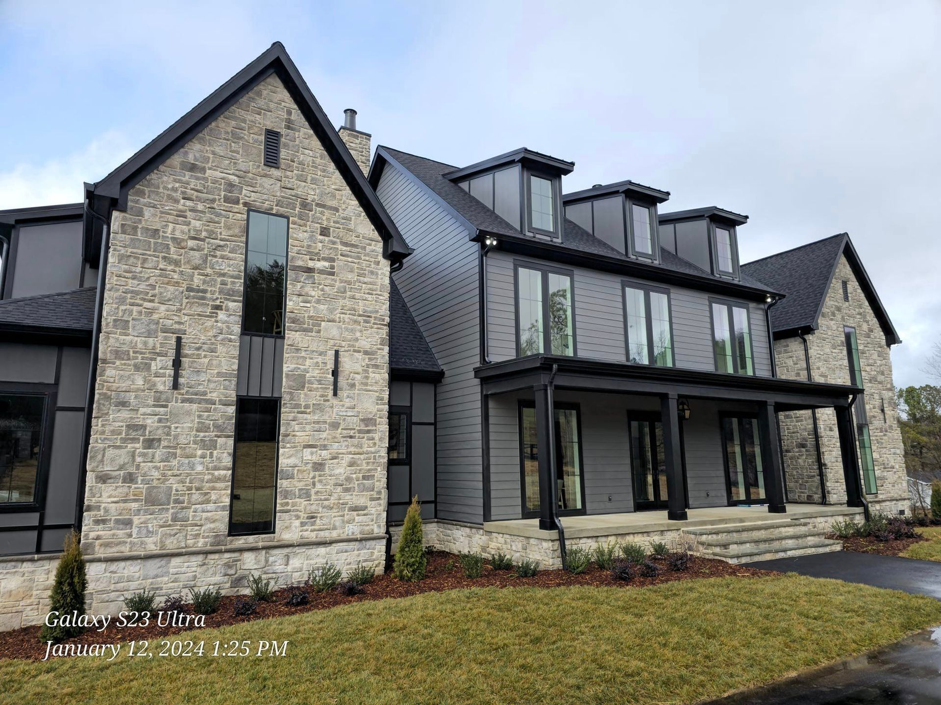 Gray and stone modern home with black trim and accents.