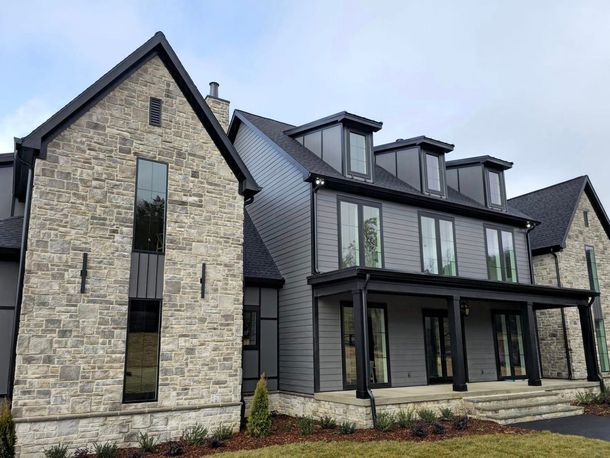 Modern gray and stone house with black trim and roof.