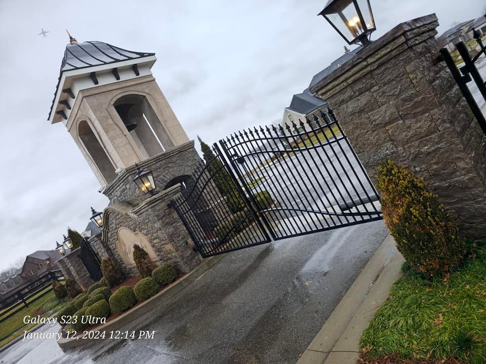 Stone entrance with black wrought iron gate and a tower with a dark roof.