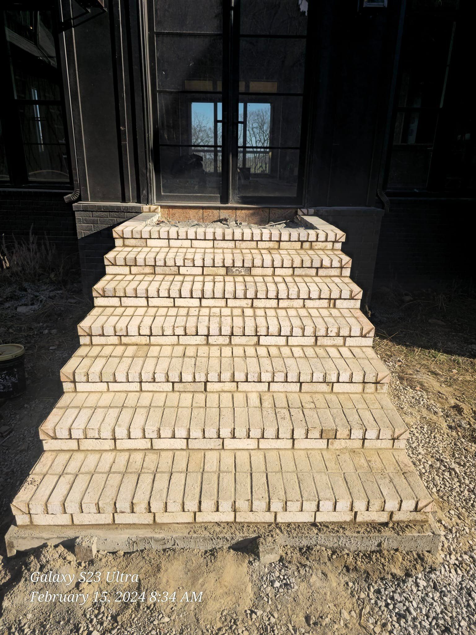 Brick steps leading up to a dark building's glass door.