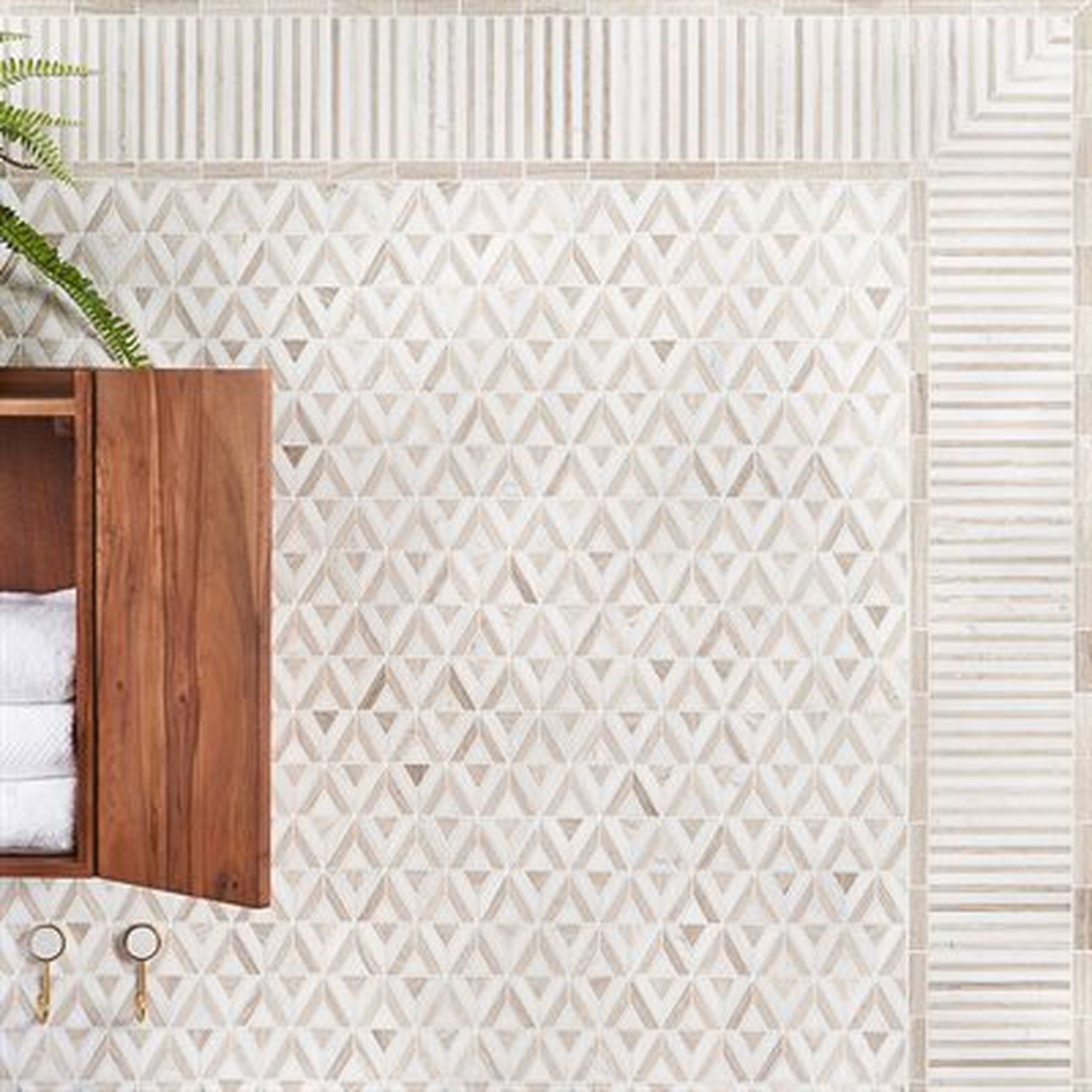 Bathroom with geometric patterned tile, wooden cabinet, and towels.