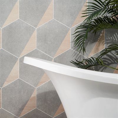 Grey and wood-tone hexagonal tiles on a bathroom wall with a white tub and green plant.