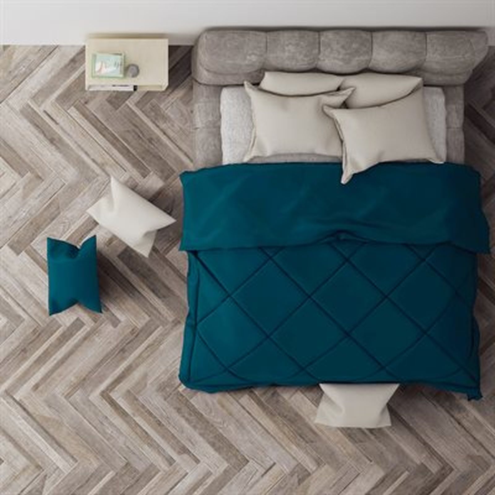 Overhead view of a bed with teal comforter, light pillows, nightstand on parquet flooring.