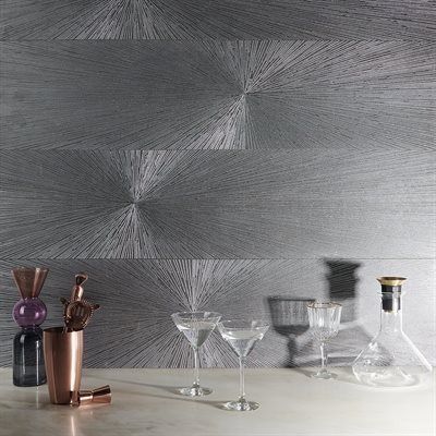 Bar setting with glassware, cocktail shaker, and textured silver wall.