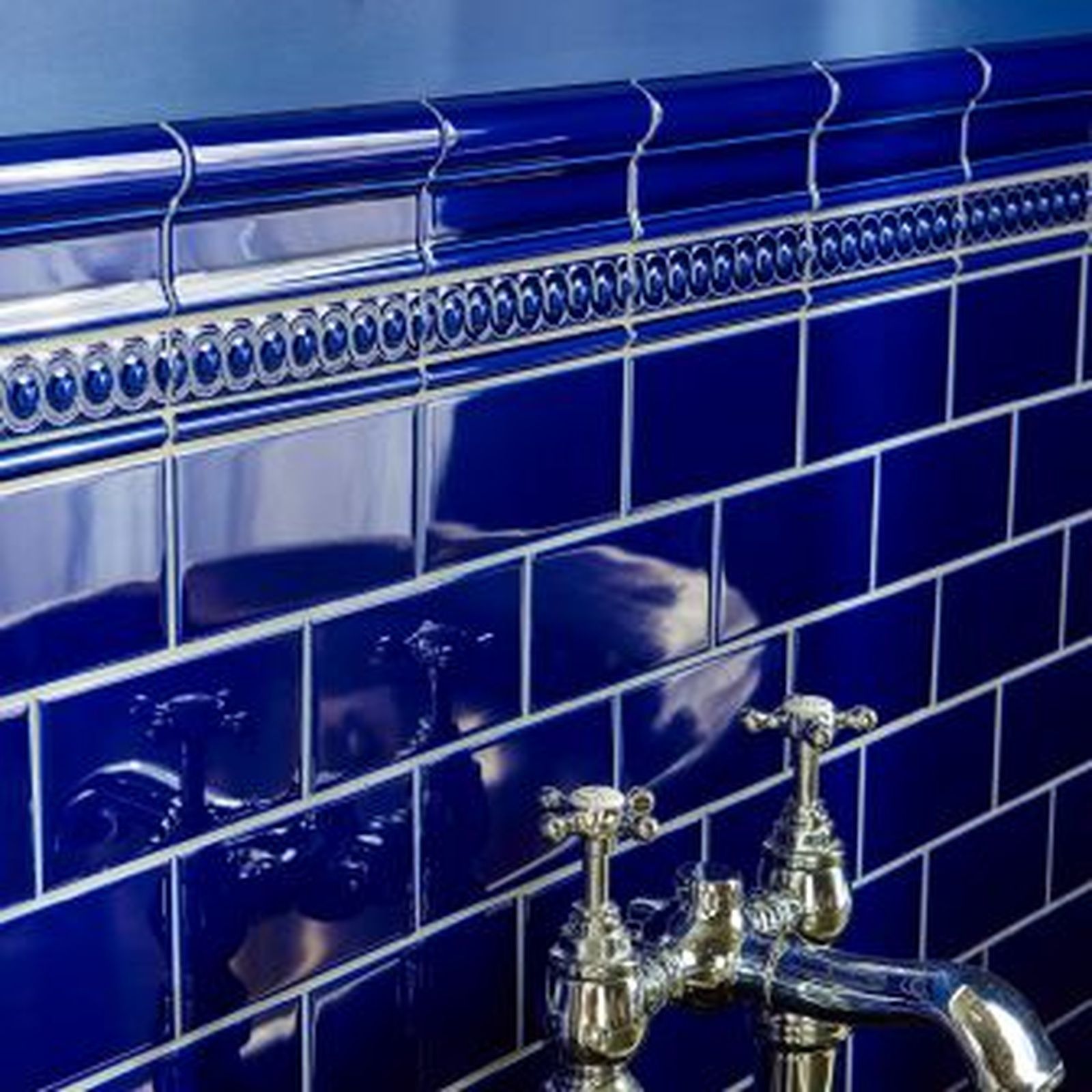 Blue tiled wall with silver fixtures.