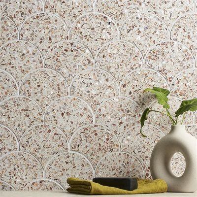 Terrazzo tile backsplash with arched white grout lines, a vase with greenery, and yellow towel.