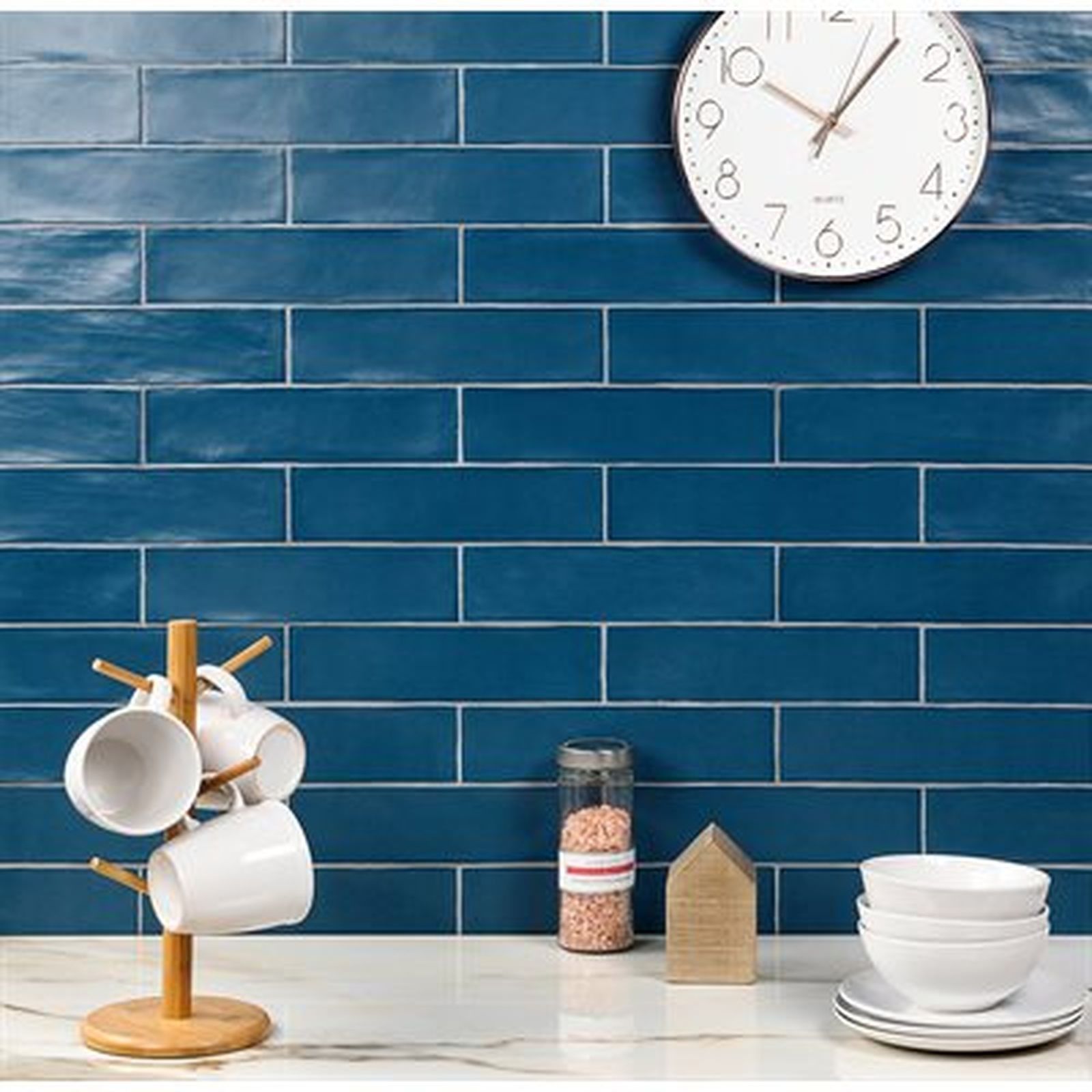 Blue tile backsplash with a white clock, mugs, and dishes.