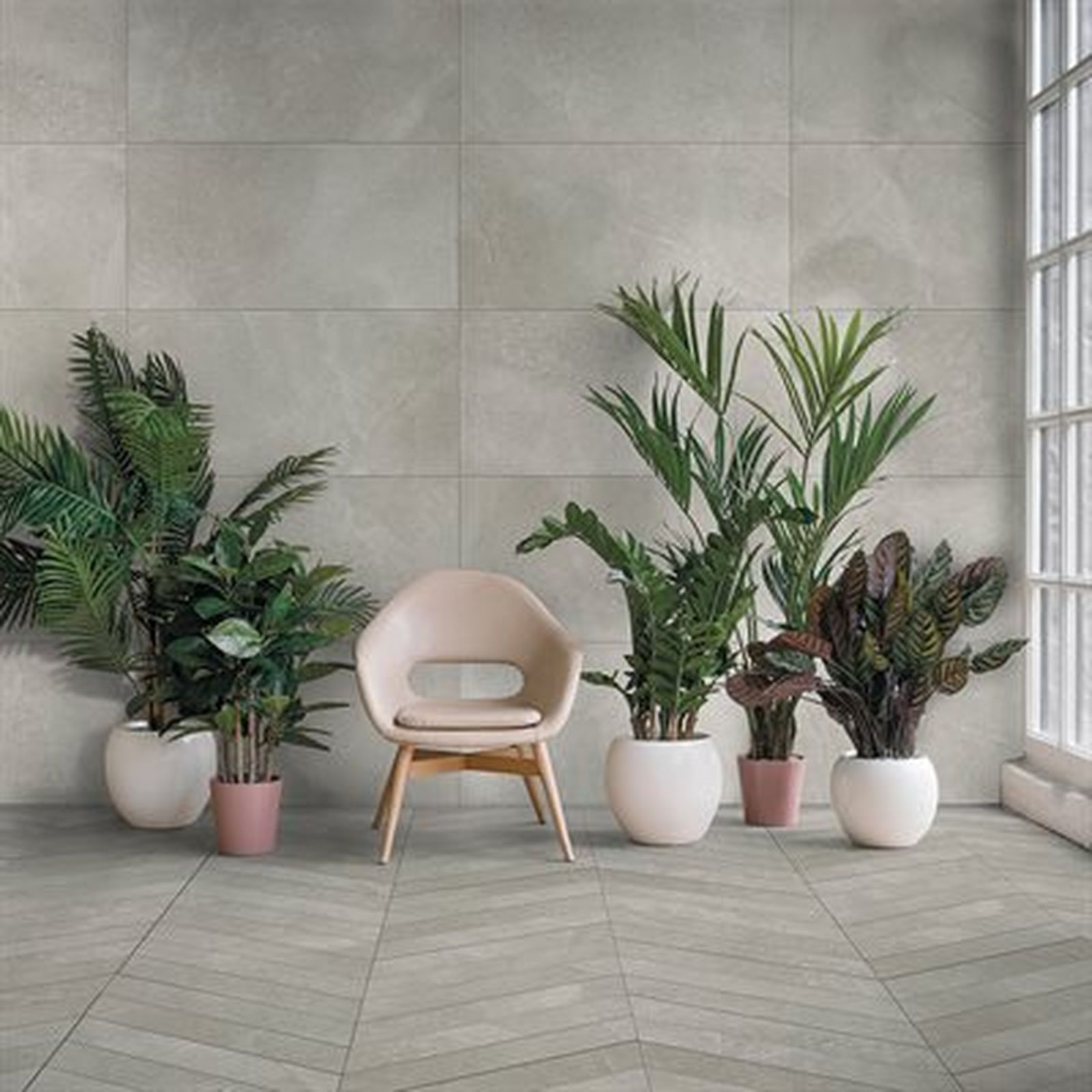 Indoor space with potted plants, chair, and gray tiled walls and floor, near a window.