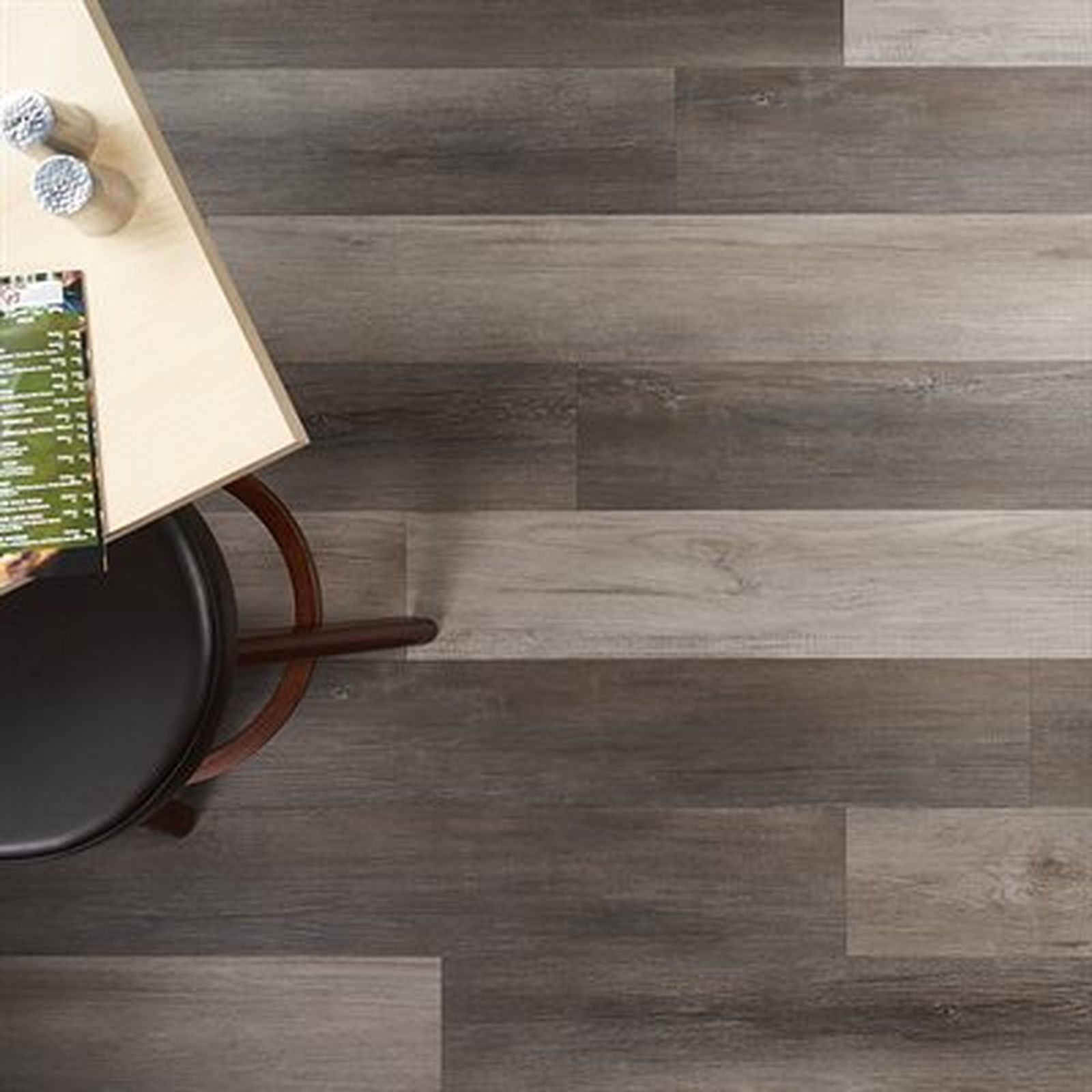 Overhead view of a table with a chair, set on a floor with gray wood planking.