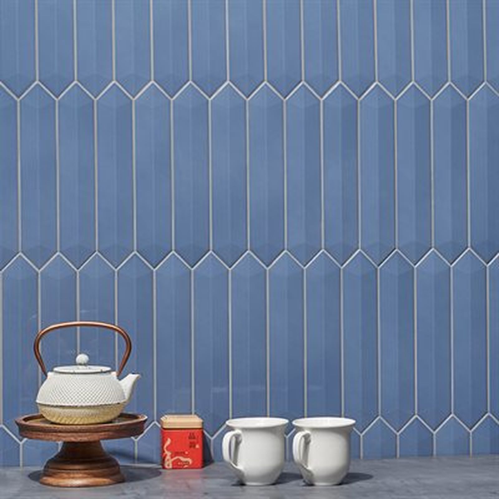 Blue elongated picket tiles with teapot, cups, and small container.