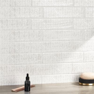 White tile wall with patterned surface, a black bottle, and a brush.